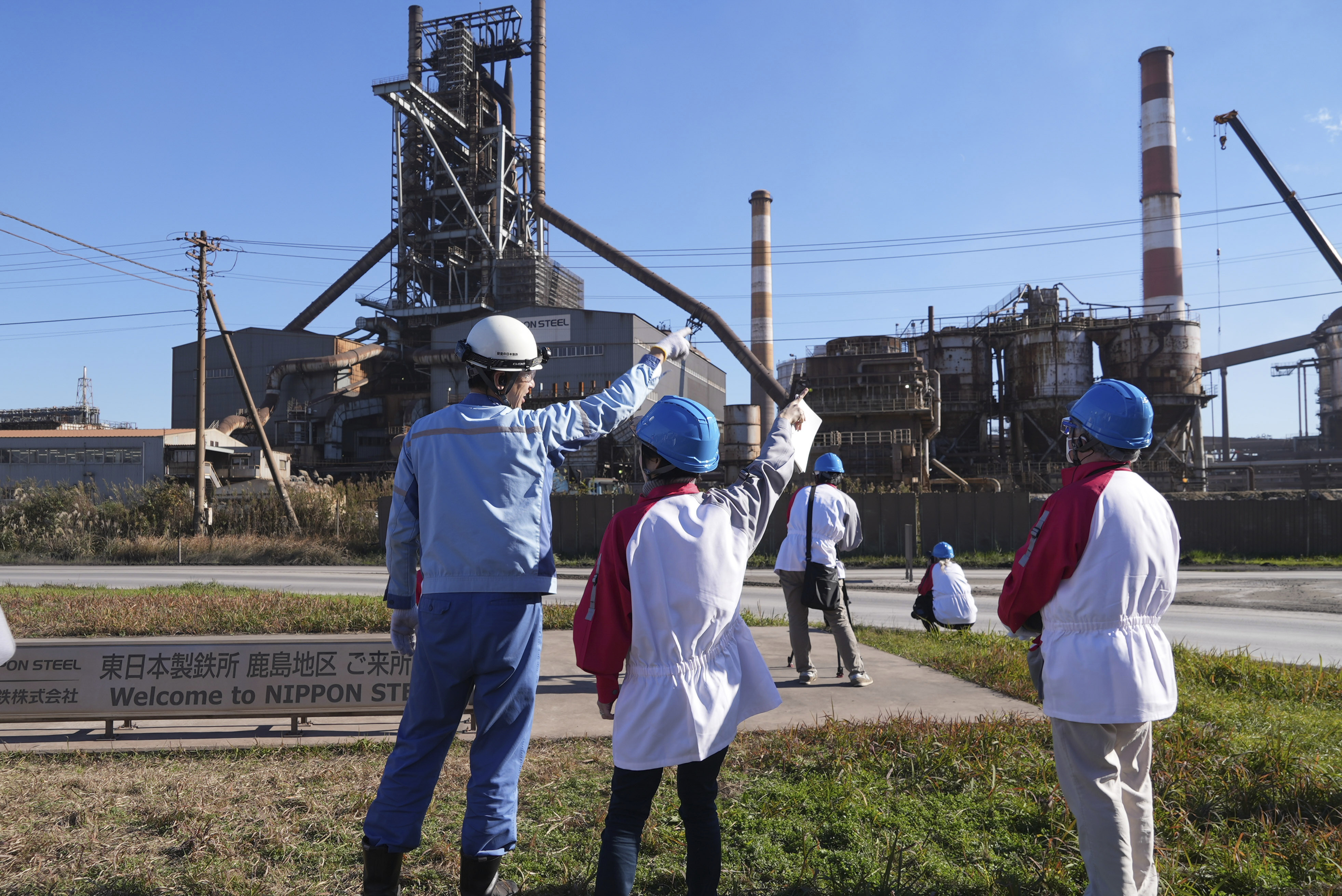 A Nippon Steel staff member, left, points in front of the company's Blast Furnace No. 1 at its Kashima Plant in Kashima, Japan on Friday, Dec. 6, 2024. (AP Photo/Ayaka McGill)