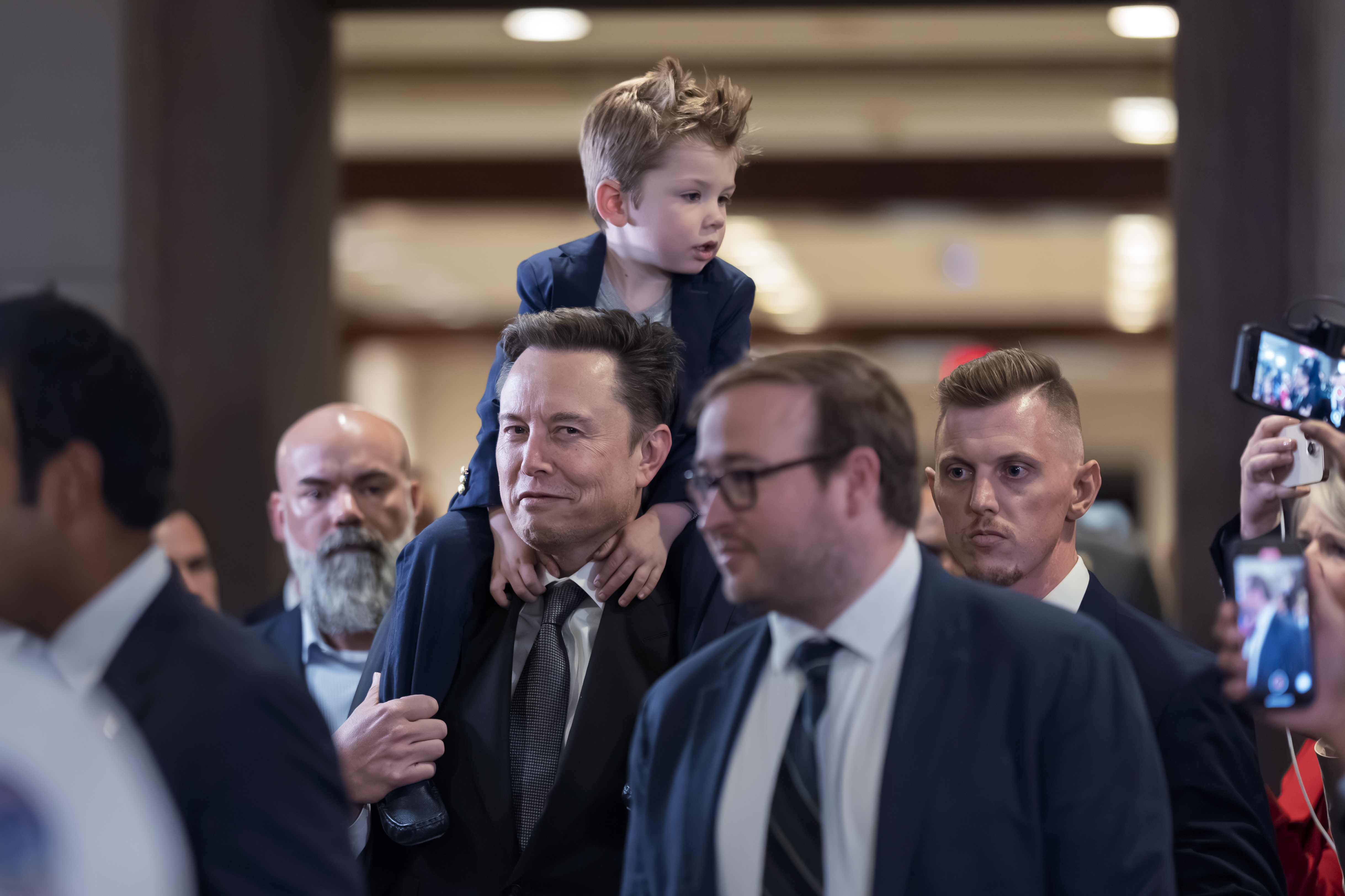 Elon Musk carries his son X Æ A-Xii, after a meeting about President-elect Donald Trump's planned Department of Government Efficiency, or DOGE, at the Capitol in Washington, Thursday, Dec. 5, 2024. (AP Photo/J. Scott Applewhite)