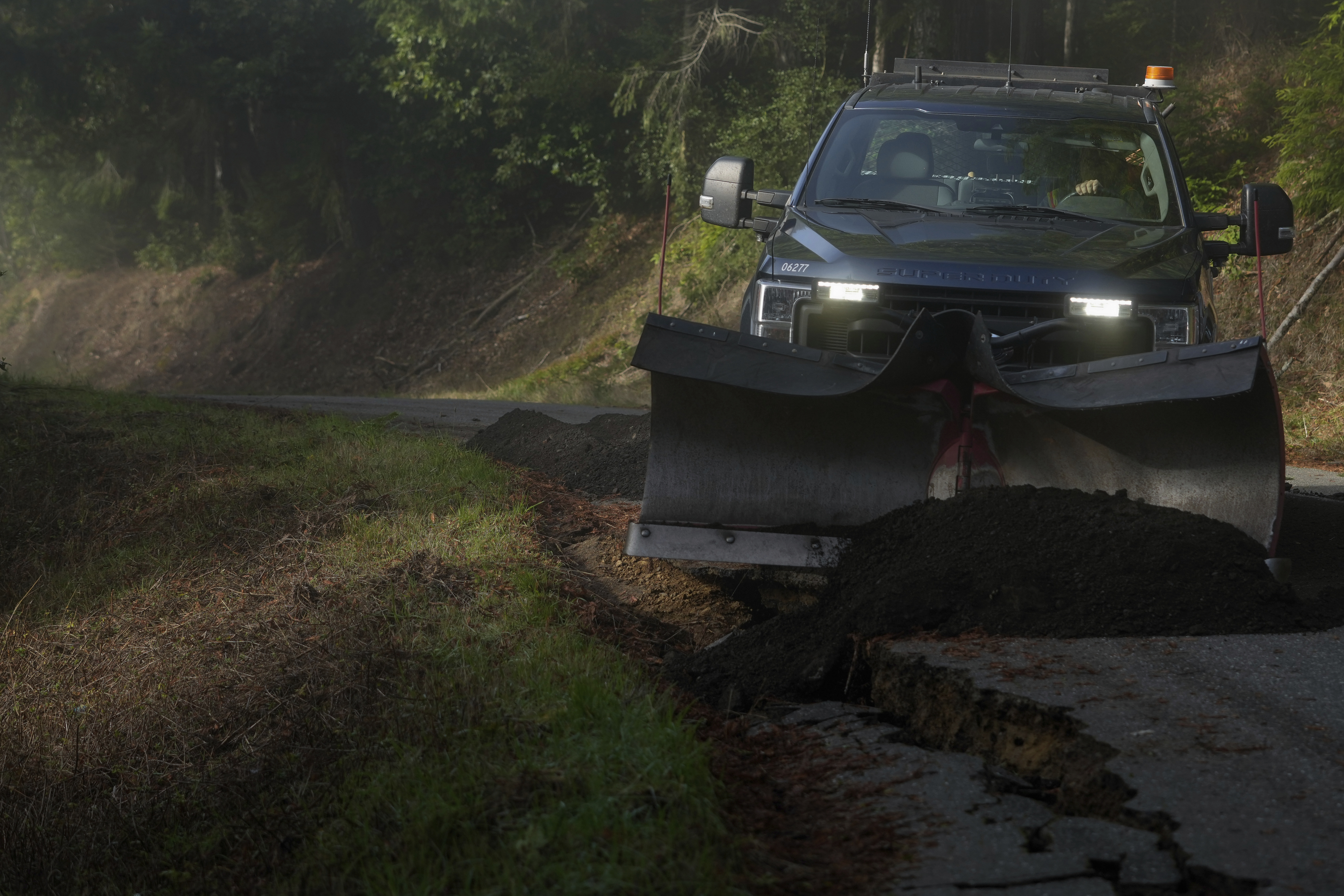 Humboldt County road maintenance supervisor Wayne Tomasini fills in cracks with dirt on a road damaged by a 7.0 earthquake in Humboldt County, Calif., Friday, Dec. 6, 2024. (AP Photo/Godofredo A. Vásquez)