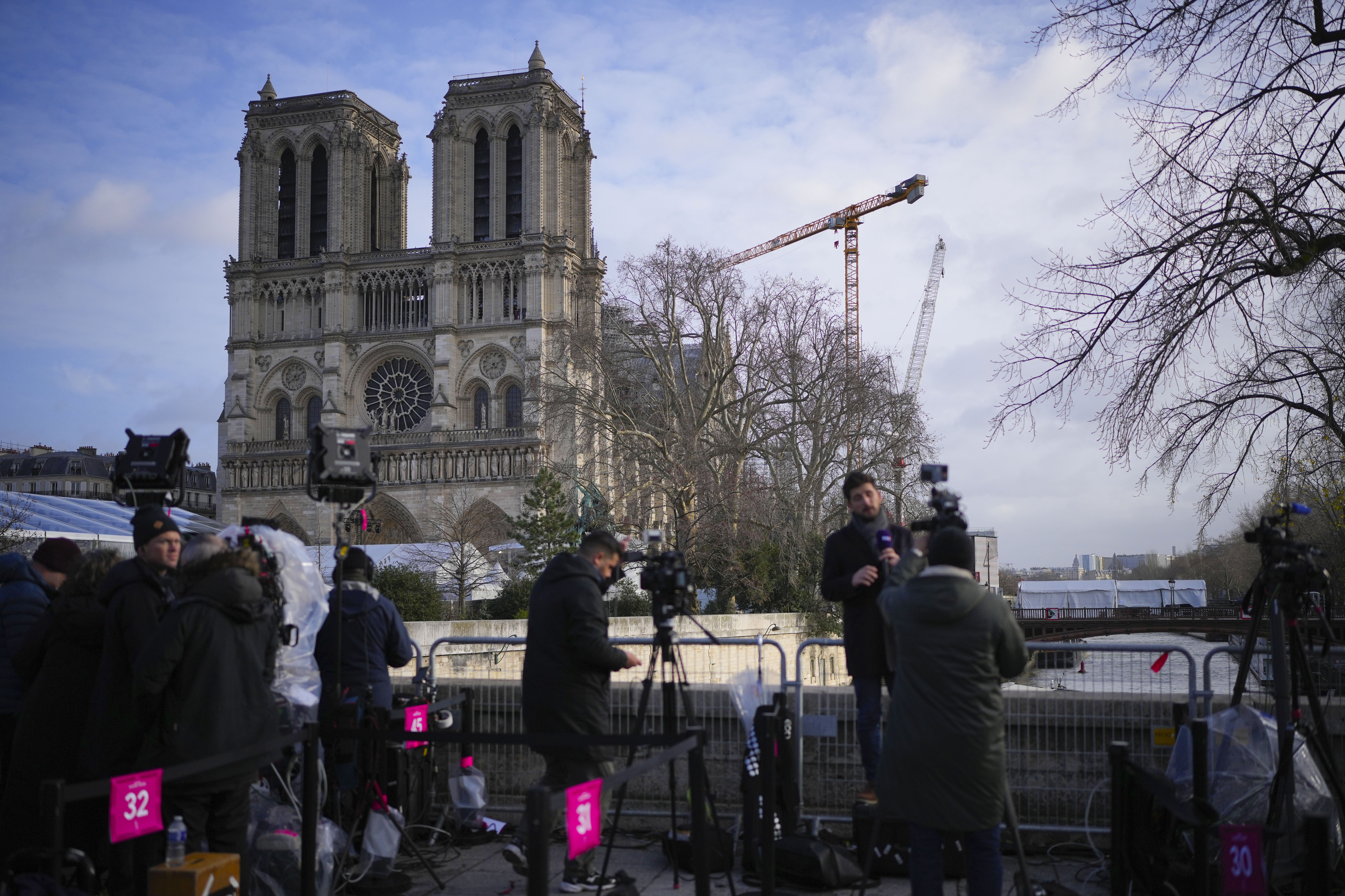 Journalists stand in front of Notre Dame Cathedral on the day of its ceremonial reopening in Paris, Saturday, Dec. 7, 2024, following the devastating fire of 2019. (AP Photo/Alessandra Tarantino)