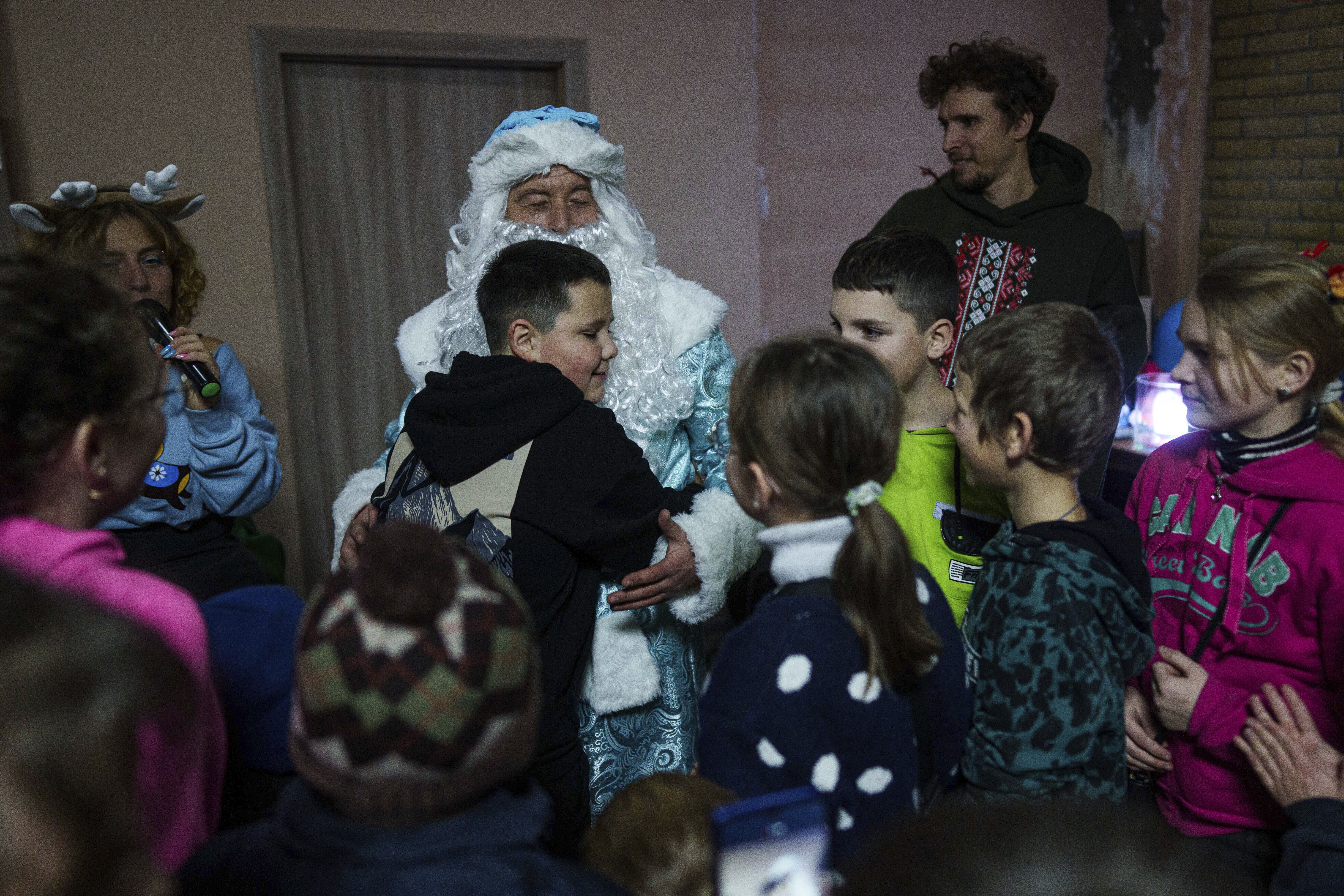 A boy hugs a man wearing a St. Nicholas costume during celebrations of St. Nicholas Day in Izium, Ukraine, Dec. 6, 2024. (AP Photo/Evgeniy Maloletka)