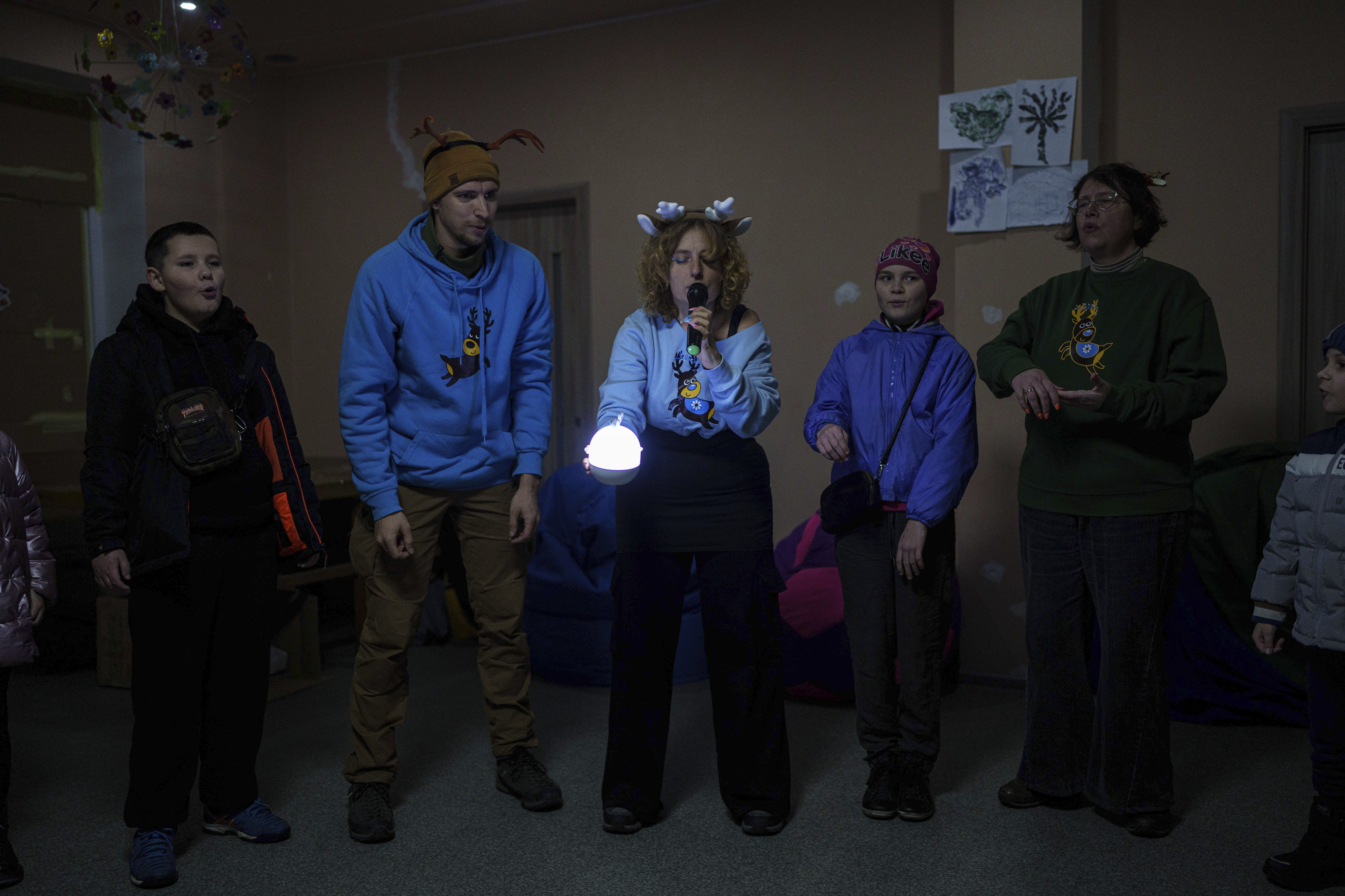 Kateryna Shutalova, center, a psychologist of the NGO Ukrainian Frontiers, performs in front of children during celebrations of St. Nicholas Day in Izium, Ukraine, Dec. 6, 2024. (AP Photo/Evgeniy Maloletka)