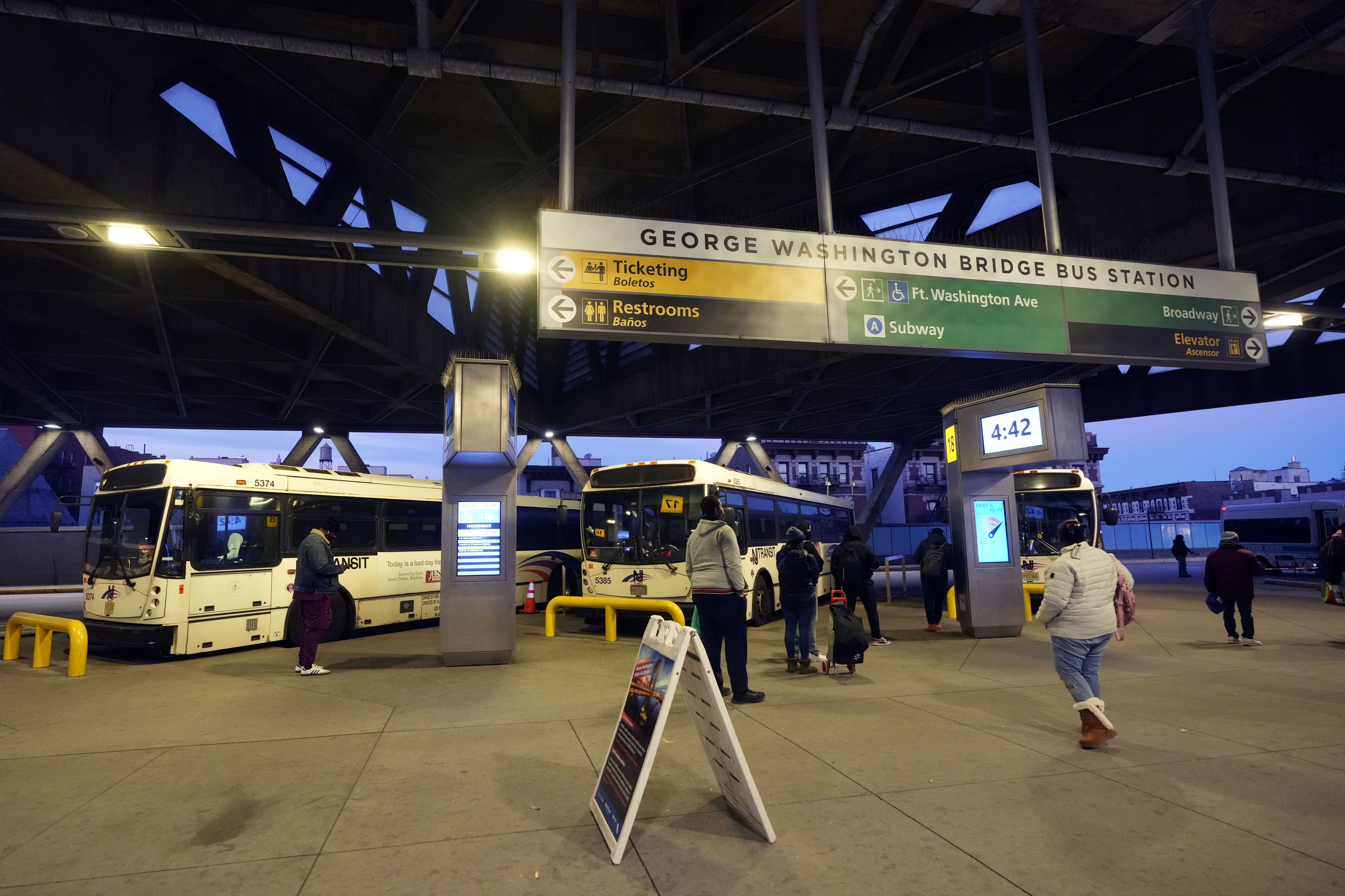 Commuters wait for buses at the George Washington Bridge Bus Station in New York, Friday, Dec. 6, 2024, where the gunman fleeing Wednesday's shooting of UnitedHealthcare CEO Brian Thompson took a taxi to, according to surveillance video. (AP Photo/Richard Drew)