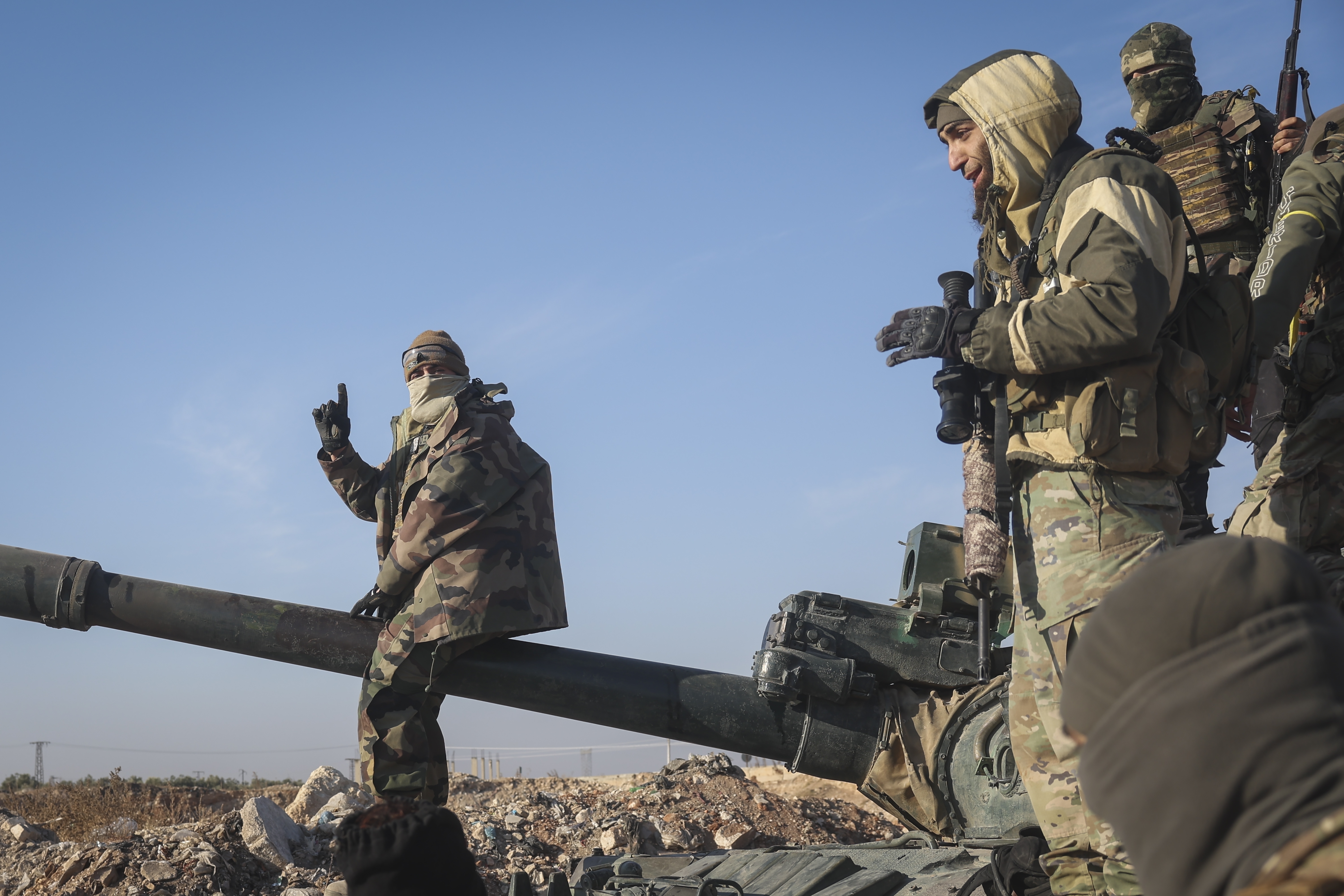 Syrian opposition fighters stand atop a seized military armored vehicle on the outskirts of Hama, Syria, Tuesday, Dec. 3, 2024. (AP Photo/Ghaith Alsayed)