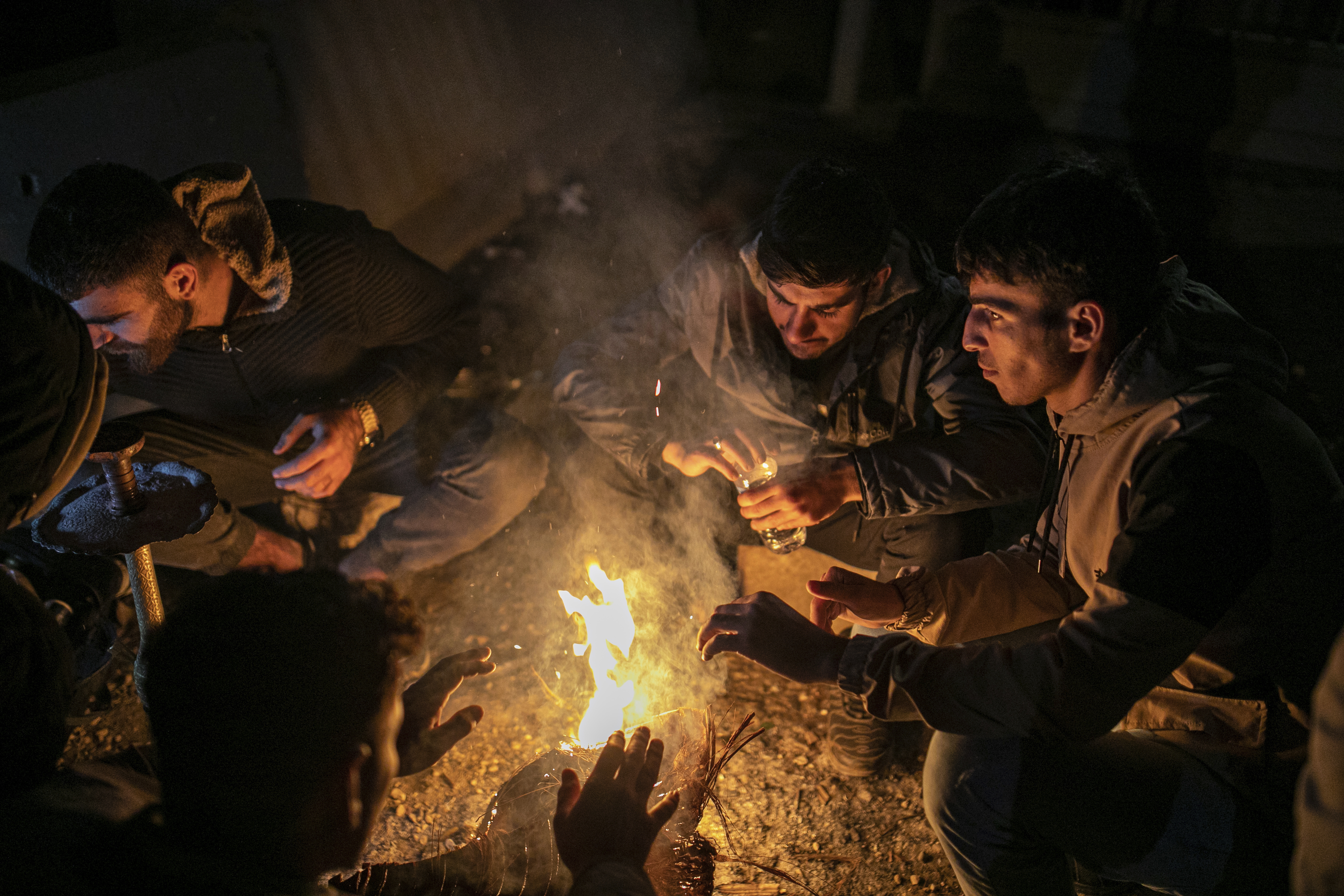 Syrians get warm as they wait overnight to cross into Syria from Turkey at the Cilvegozu border gate, near the town of Antakya, southern Turkey, Sunday, Dec. 8, 2024. (AP Photo/Metin Yoksu)