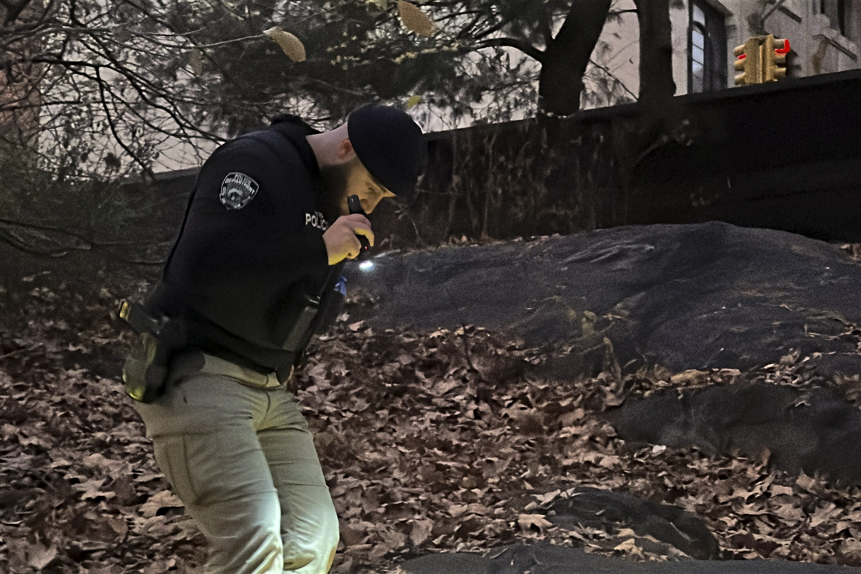 A New York City Police officer walks through brush and foliage in Central Park near 64th Street and Central Park West, Friday, Dec. 6, 2024, in New York, while searching for a backpack police believe was dropped in the park by the person suspected of killing UnitedHealthcare CEO Brian Thompson on Wednesday, Dec. 4, 2024. (AP Photo/Ted Shaffrey)