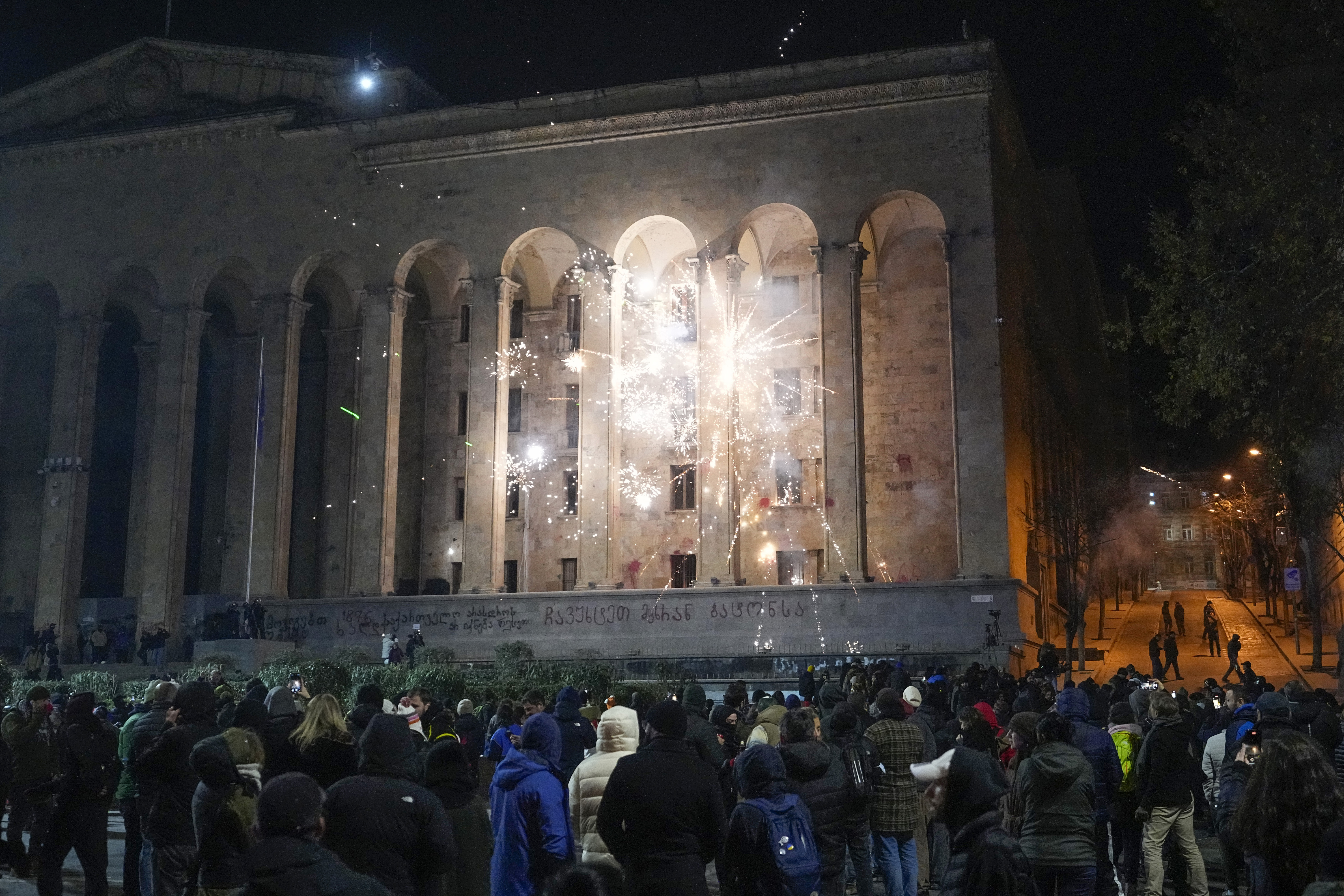 Demonstrators launch firecrackers at the Parliament during a protest against the government's decision to suspend negotiations on joining the European Union in Tbilisi, Georgia, Sunday, Dec. 8, 2024. (AP Photo/Pavel Bednyakov)