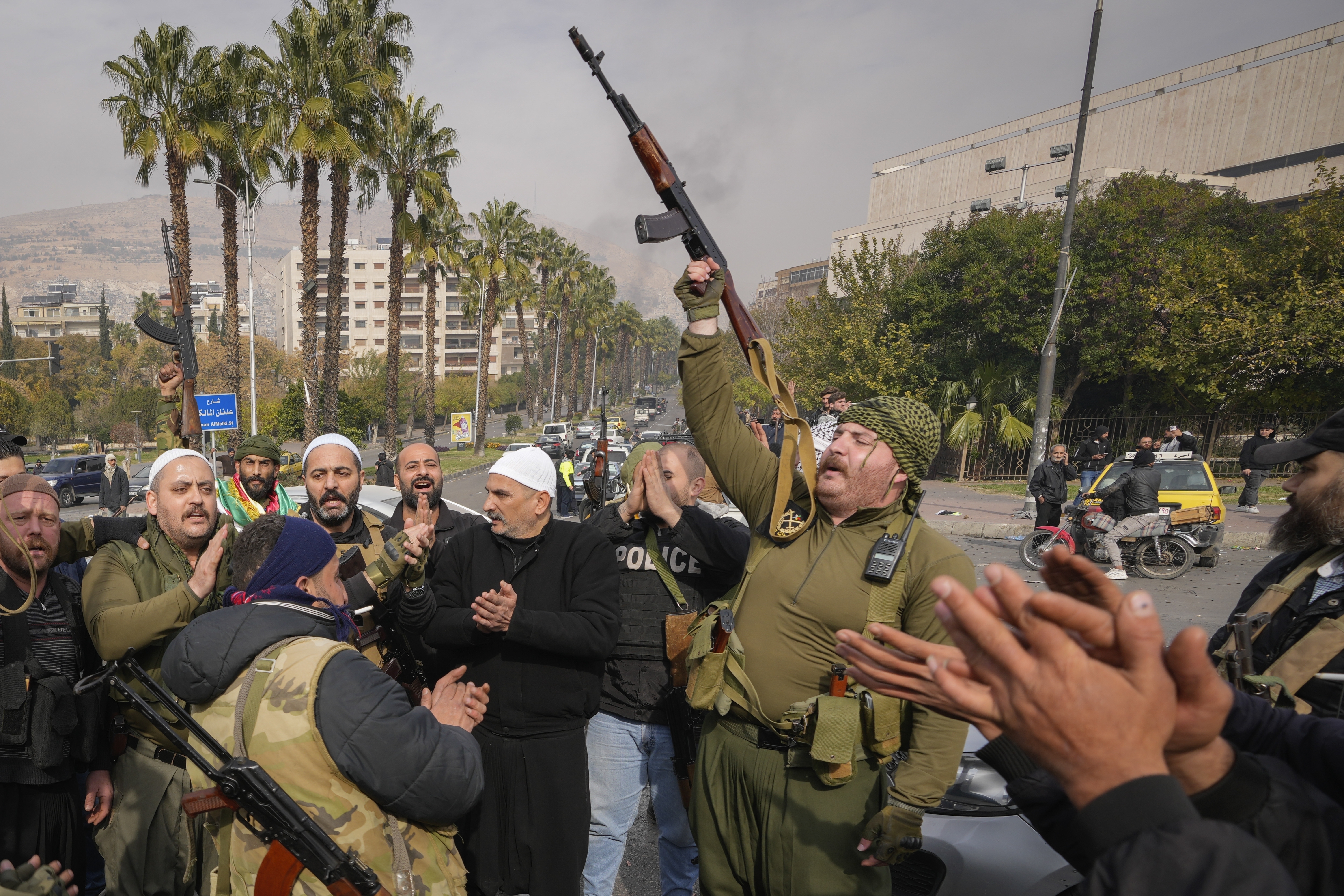 Opposition fighters celebrate the take over of the city by the insurgents in Damascus, Syria, Sunday Dec. 8, 2024. (AP Photo/Hussein Malla)