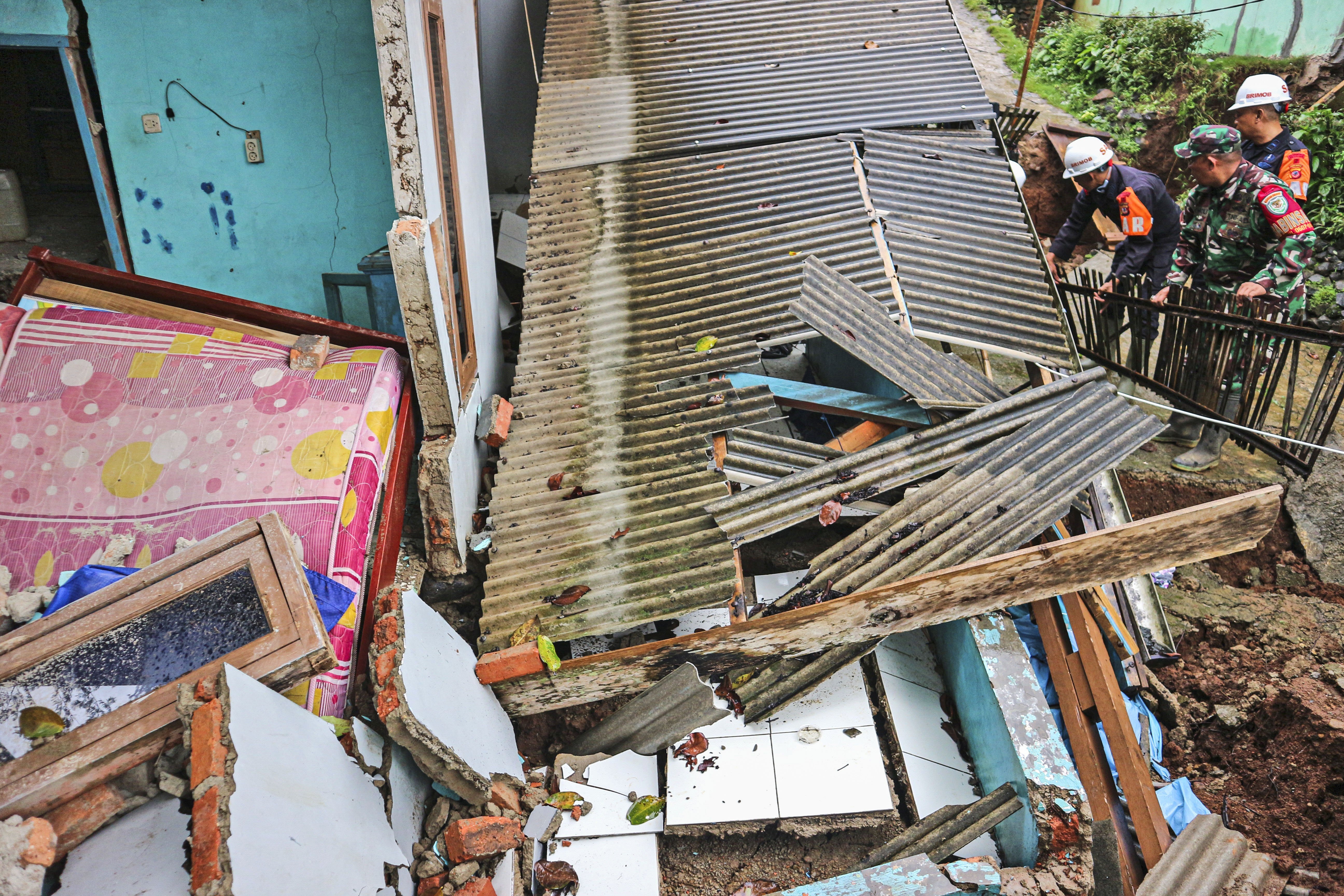 Rescuers clear up rubble from damaged houses at a neighborhood affected by a landslide in Sukabumi, West Java, Indonesia, Monday, Dec. 9, 2024. (AP Photo/Rangga Firmansyah)