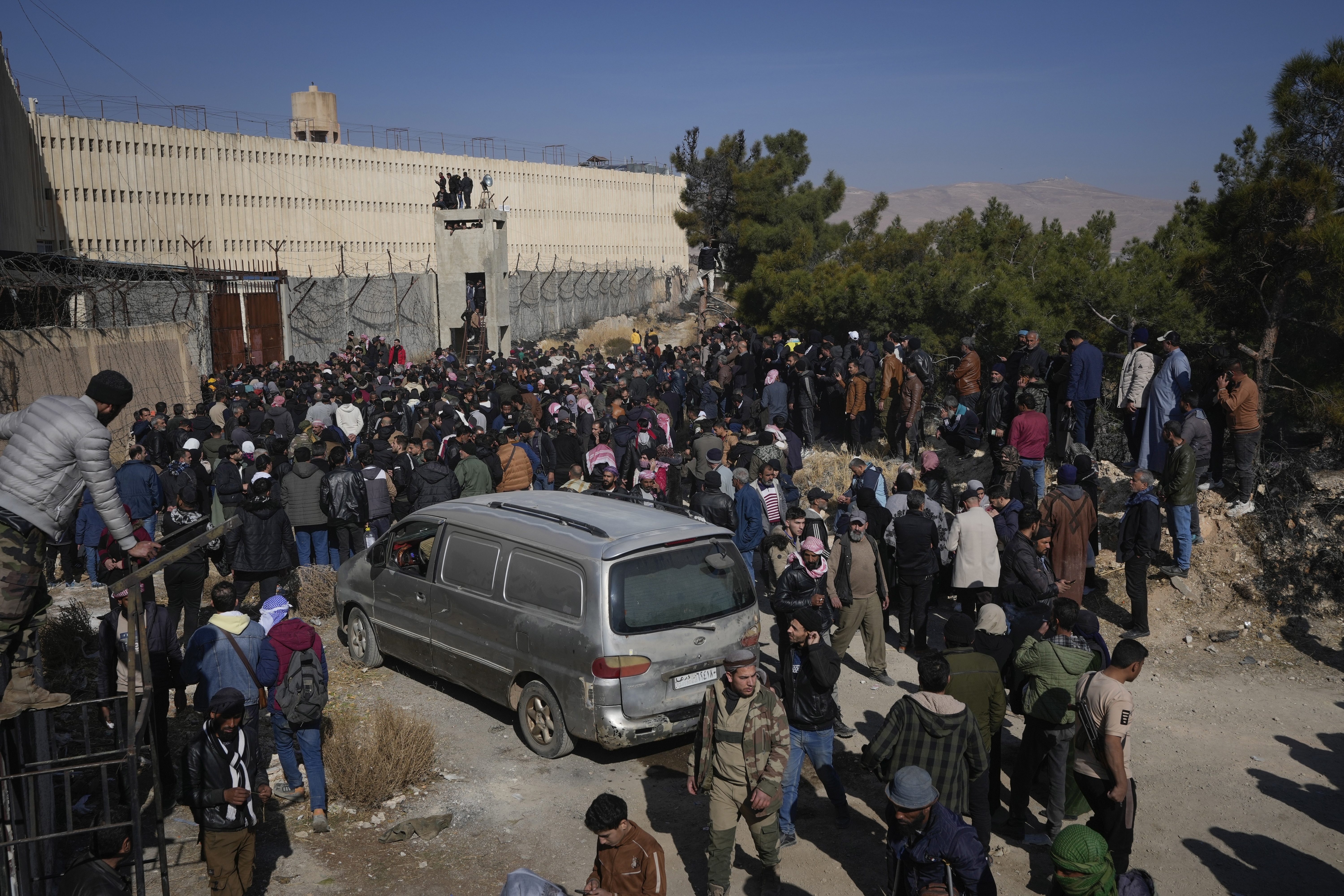 People stand outside the infamous Saydnaya military prison, just north of Damascus, Syria, Monday, Dec. 9, 2024. Crowds are gathering to enter the prison, known as the "human slaughterhouse," some hoping to find relatives who were held there, after thousands of inmates were released following the rebels' overthrow of Bashar Assad's regime on Sunday. (AP Photo/Hussein Malla)