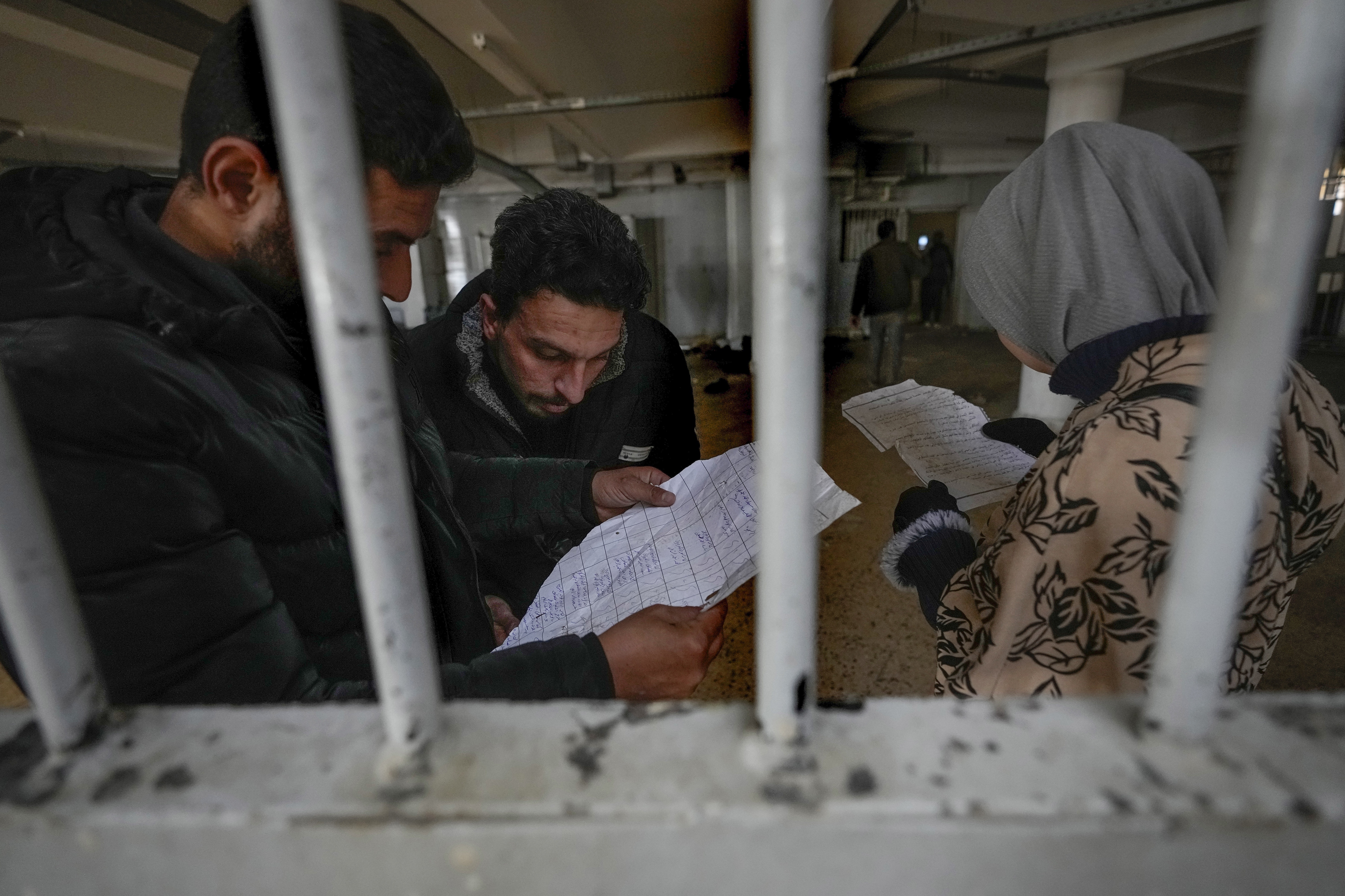 People inspect documents they found in the infamous Saydnaya military prison, just north of Damascus, Syria, Monday, Dec. 9, 2024. Crowds are gathering to enter the prison, known as the "human slaughterhouse," after thousands of inmates were released following the rebels' overthrow of Bashar al-Assad's regime on Sunday. (AP Photo/Hussein Malla)