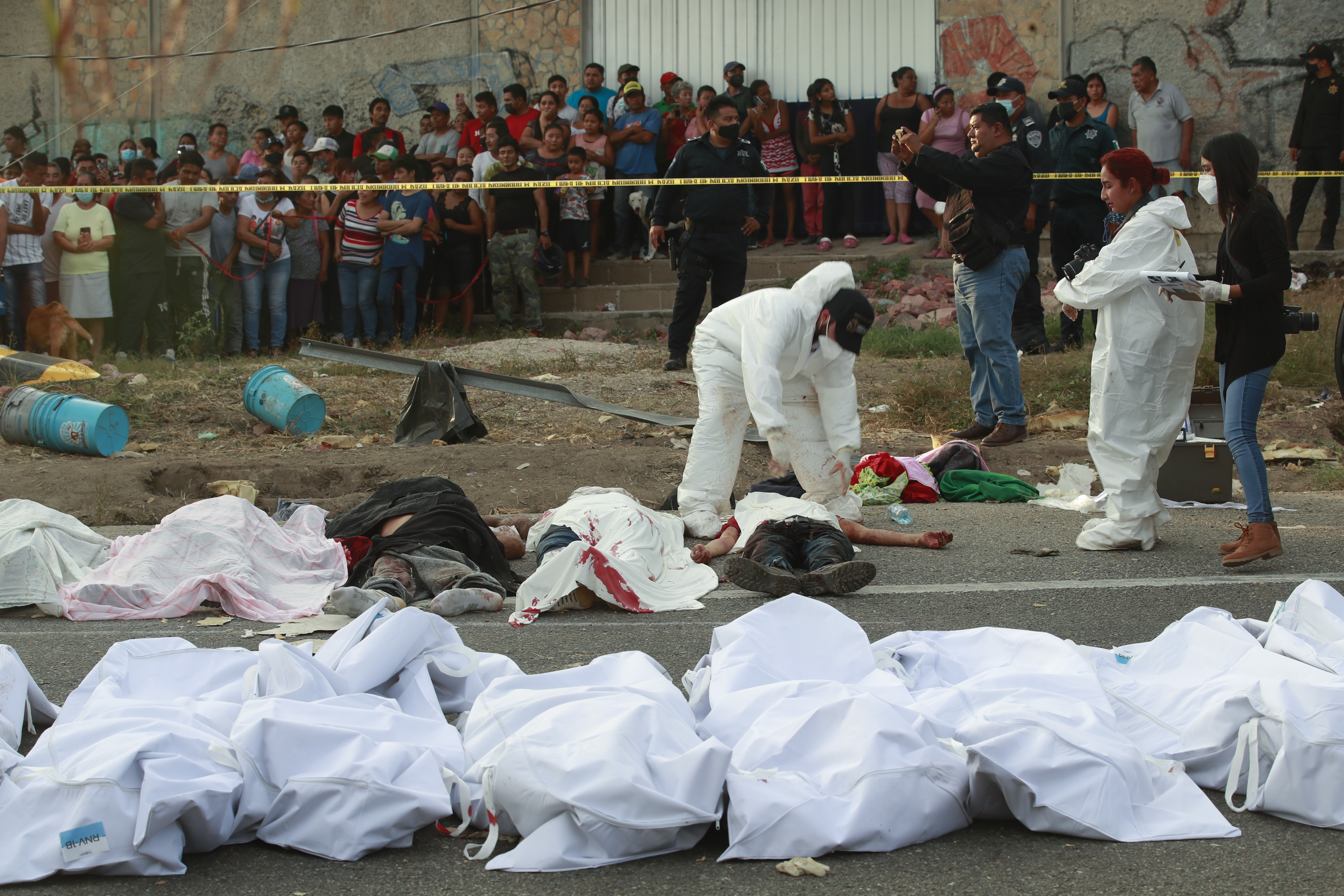 FILE - Bodies in bodybags are placed on the side of the road after a deadly semi-trailer truck crash in Tuxtla Gutierrez, Chiapas state, Mexico, Dec. 9, 2021. (AP Photo, File)