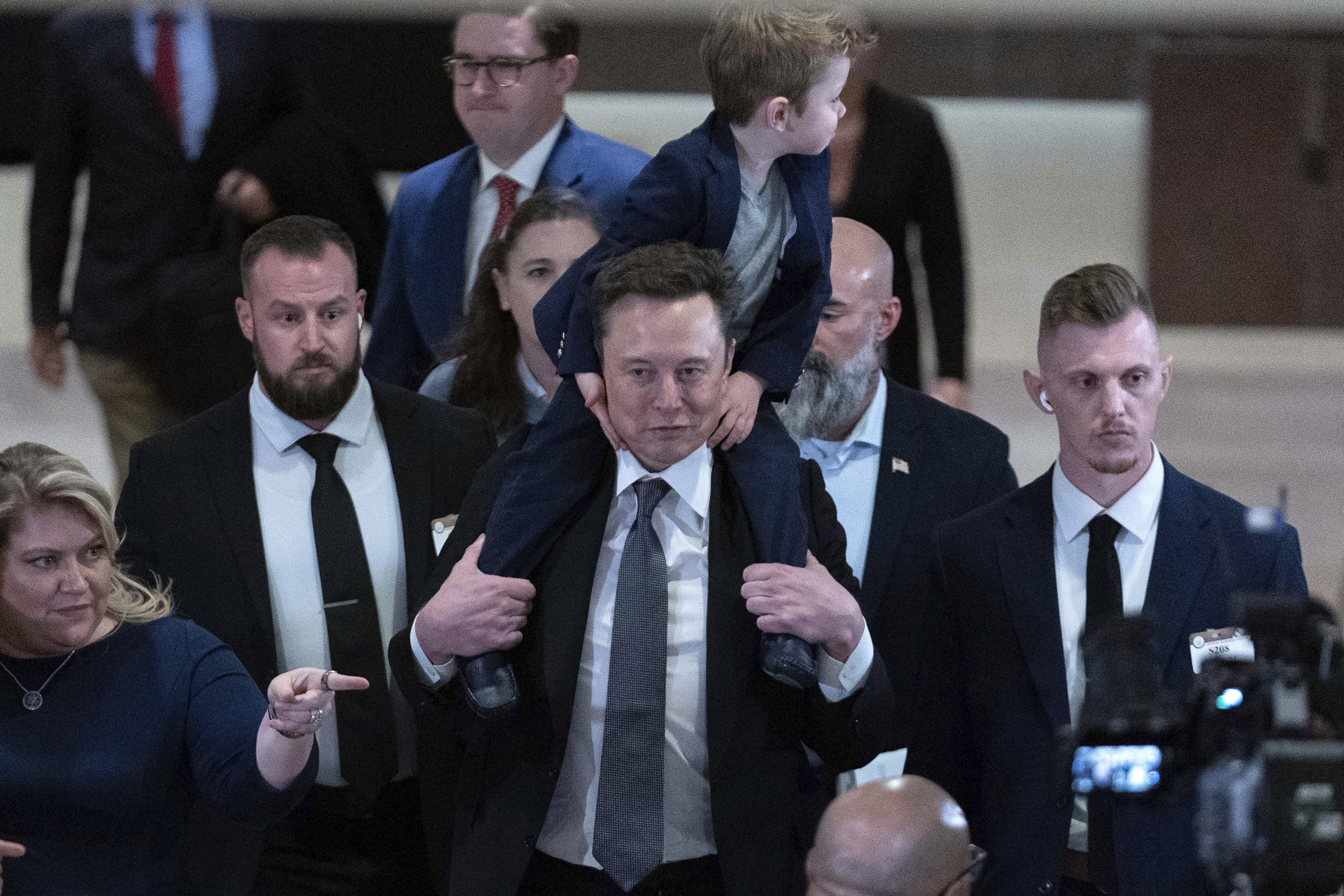 Elon Musk, carrying his son X Æ A-Xii, leaves after a meeting with members of congress to discuss President-elect Donald Trump's planned Department of Government Efficiency on Capitol Hill in Washington, Thursday, Dec. 5, 2024. (AP Photo/Jose Luis Magana)