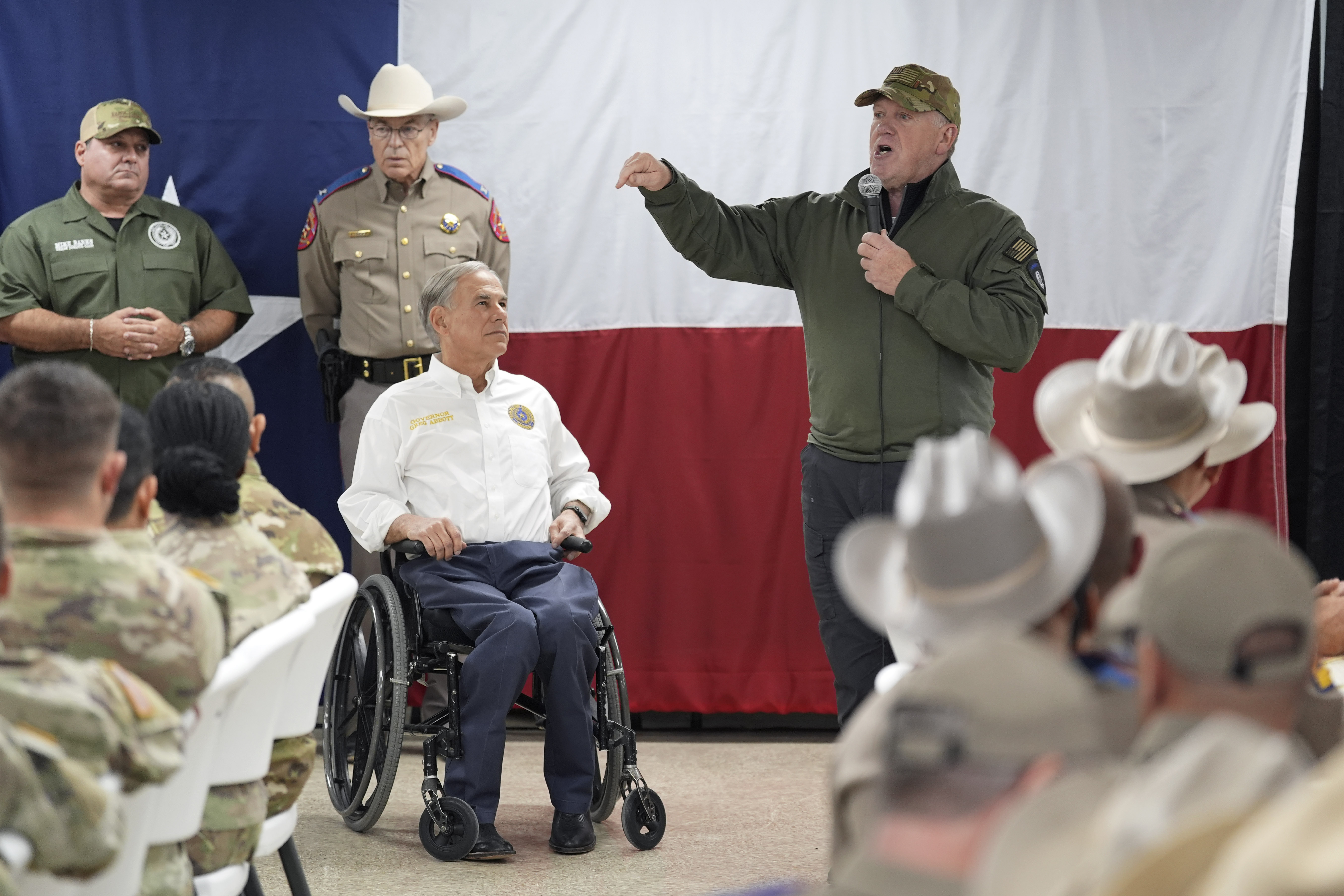 FILE - Incoming U.S. Border Czar Tom Homan, right, stands with Texas Gov. Greg Abbott, center, as he makes statements before he helped serve meals to state troopers and national guardsmen taking part in Operation Lone Star at a facility on the U.S.-Mexico border, Nov. 26, 2024, in Eagle Pass, Texas. (AP Photo/Eric Gay, File)