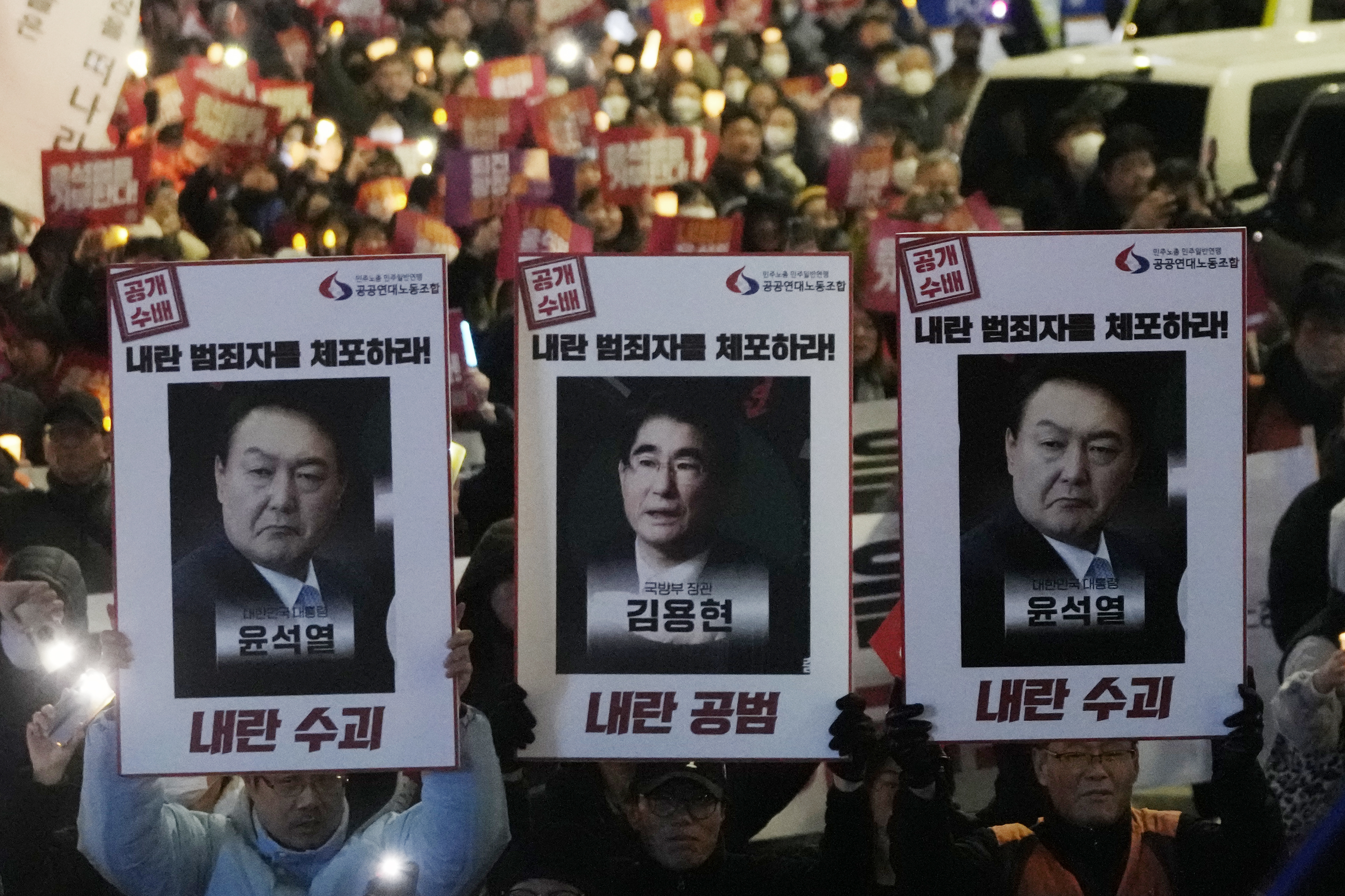 Protesters with images of South Korean President Yoon Suk Yeol and former South Korea Defense Minister Kim Yong Hyun, center, march to the presidential office after a candlelight vigil against President Yoon in Seoul, South Korea, on Dec. 5, 2024. The signs read "Arrest the rebellion criminals." (AP Photo/Ahn Young-joon)