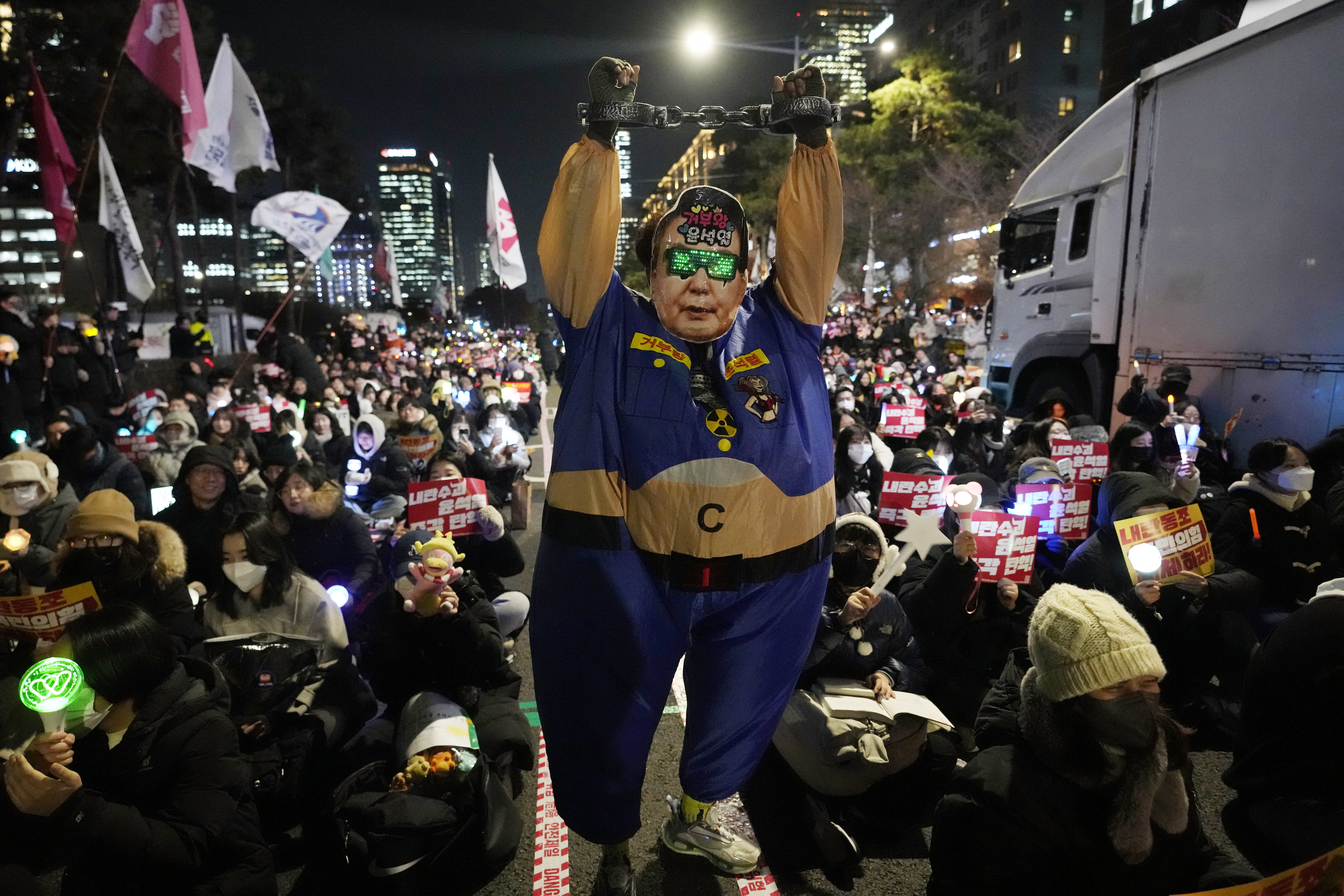 A participant wearing a mask of South Korean President Yoon Suk Yeol performs during a rally to demand his impeachment outside the National Assembly in Seoul, South Korea, Monday, Dec. 9, 2024. (AP Photo/Ahnn Young-joon)