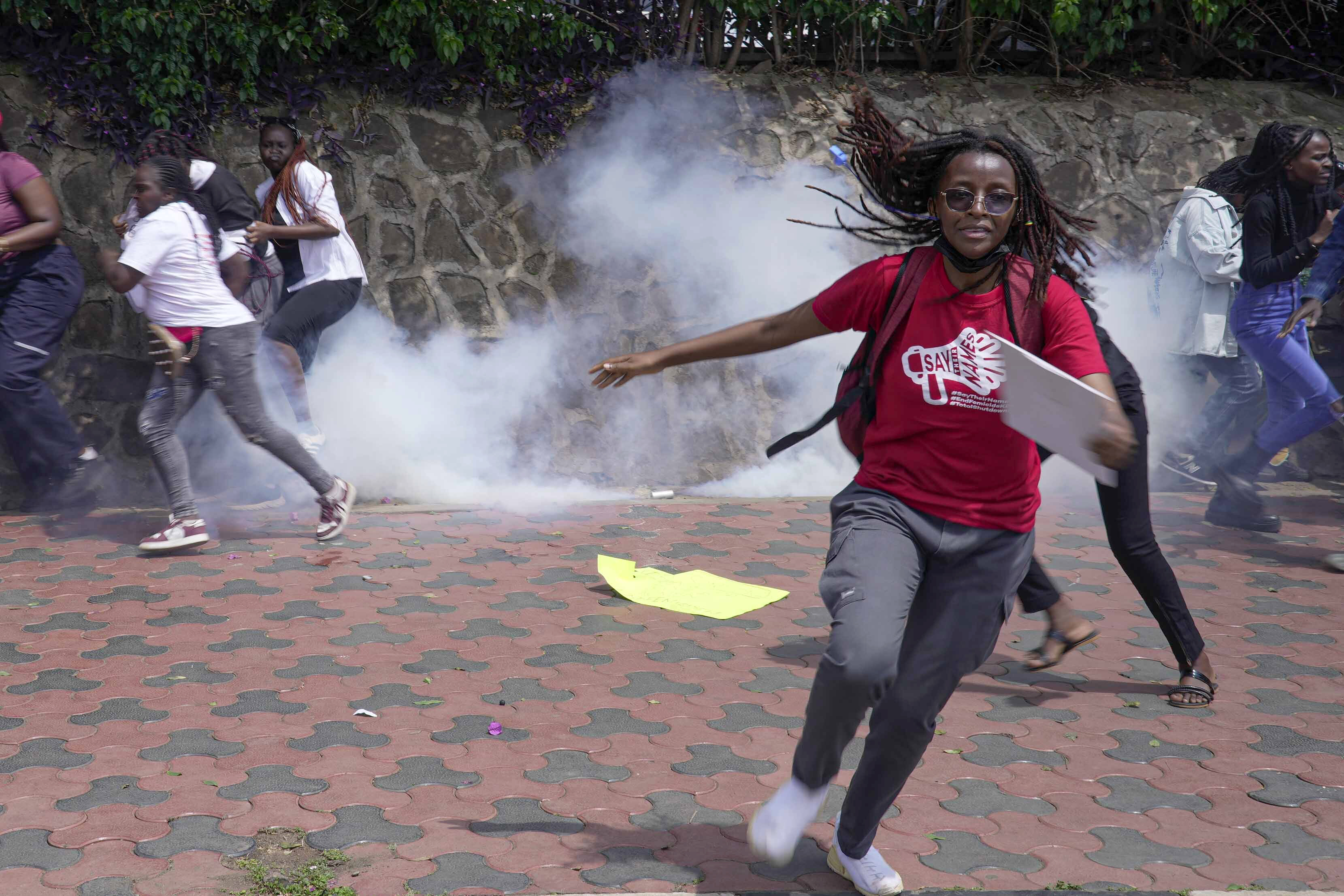 Protesters run from a cloud of tear gas fired by anti-riot police during the march against the rising cases of femicide, in downtown Nairobi, Kenya, Tuesday, Dec. 10, 2024. (AP Photo/Brian Inganga)