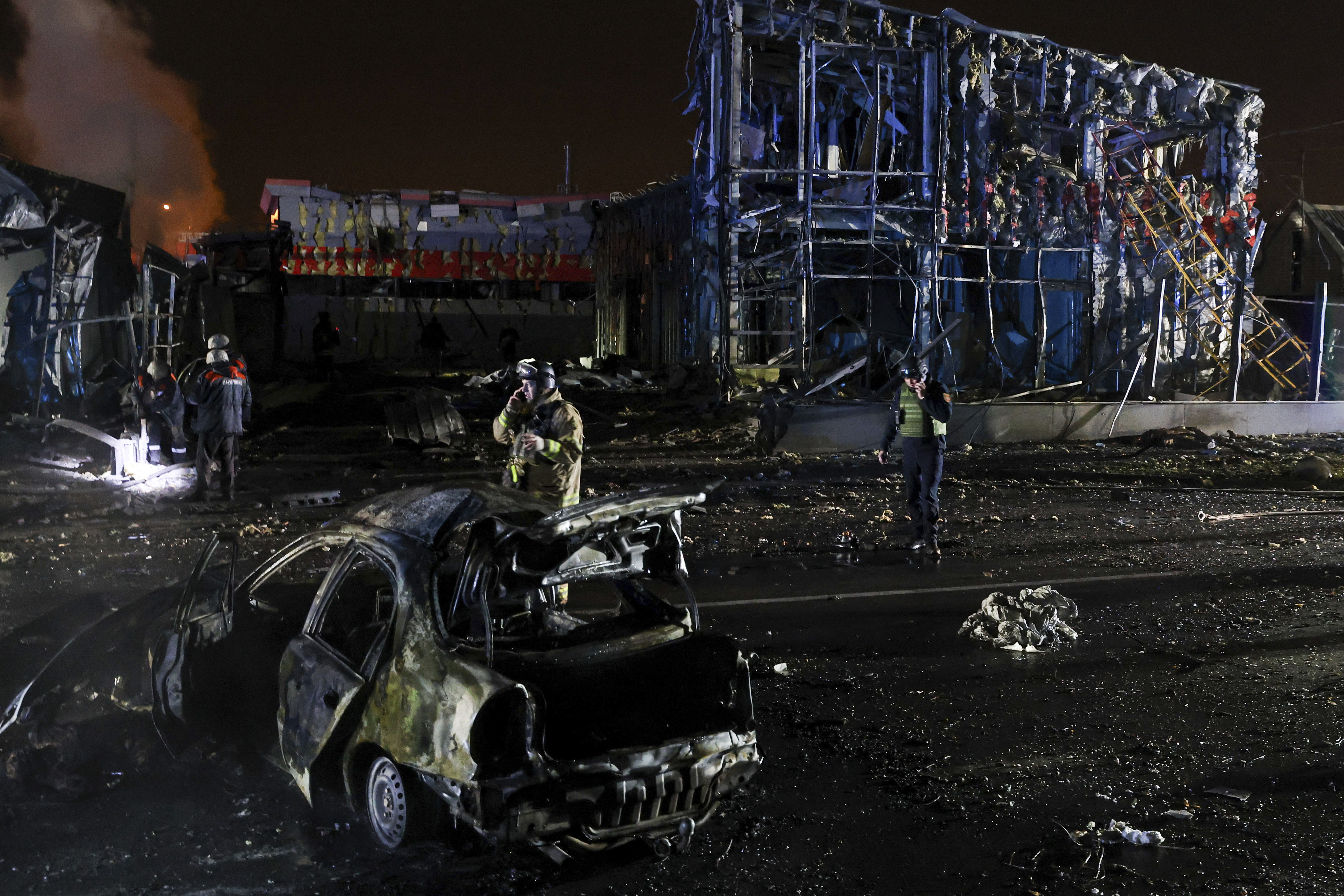 Rescue workers walk in front of a car and a building destroyed by a Russian strike in Zaporizhzhia, Ukraine, December 6, 2024. (AP Photo/Kateryna Klochko)