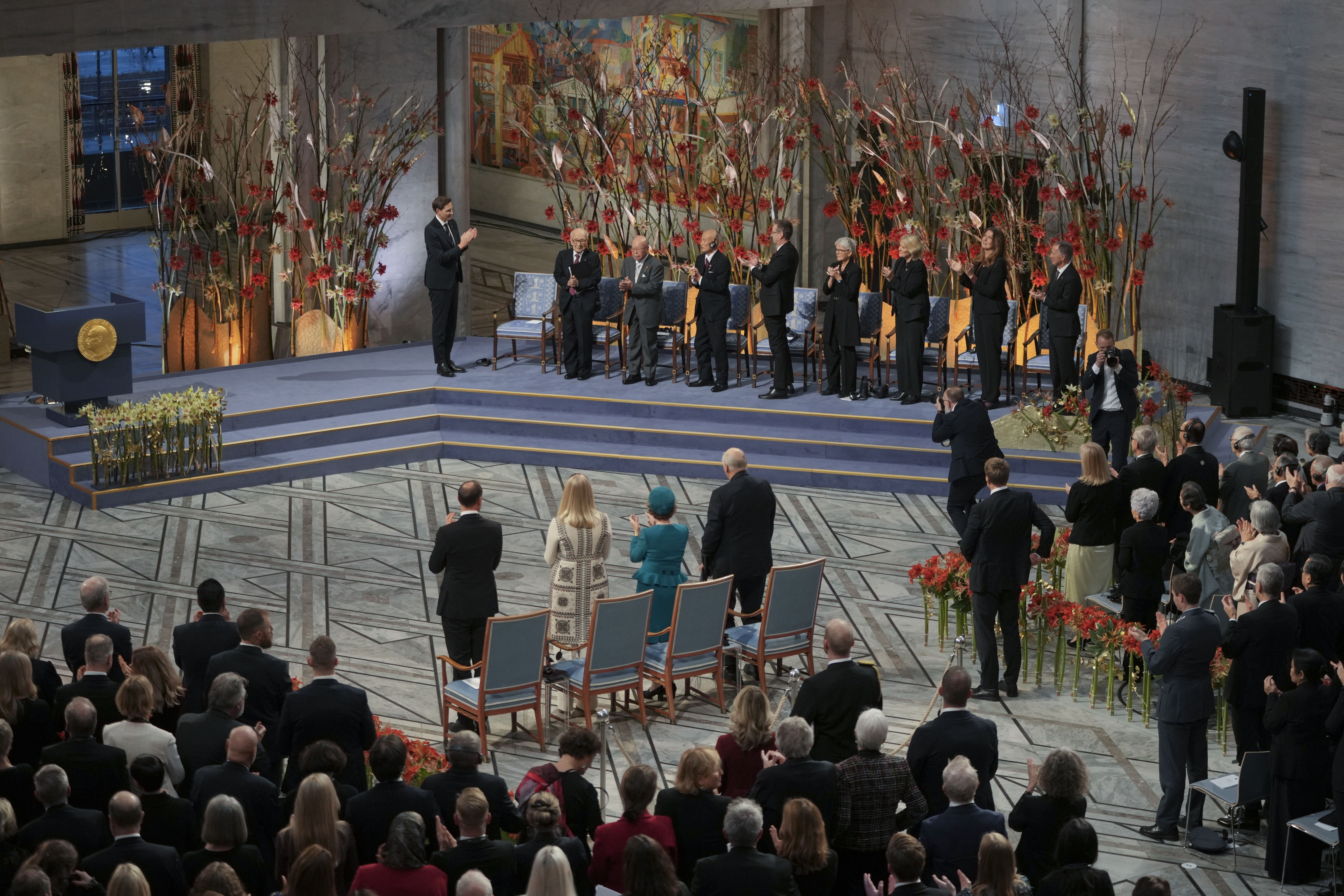 Chairman of the Nobel Committee Jørgen Watne Frydnes applauds, Terumi Tanaka, Shigemitsu Tanaka and Toshiyuki Mimaki, from left, representatives of this year's Nobel Peace Prize winner Nihon Hidankyo, or the Japan Confederation of A- and H-Bomb Sufferers Organizations, during the Nobel Peace Prize ceremony at the City Hall in Oslo, Norway, Tuesday, Dec. 10, 2024. (AP Photo/Kin Cheung)