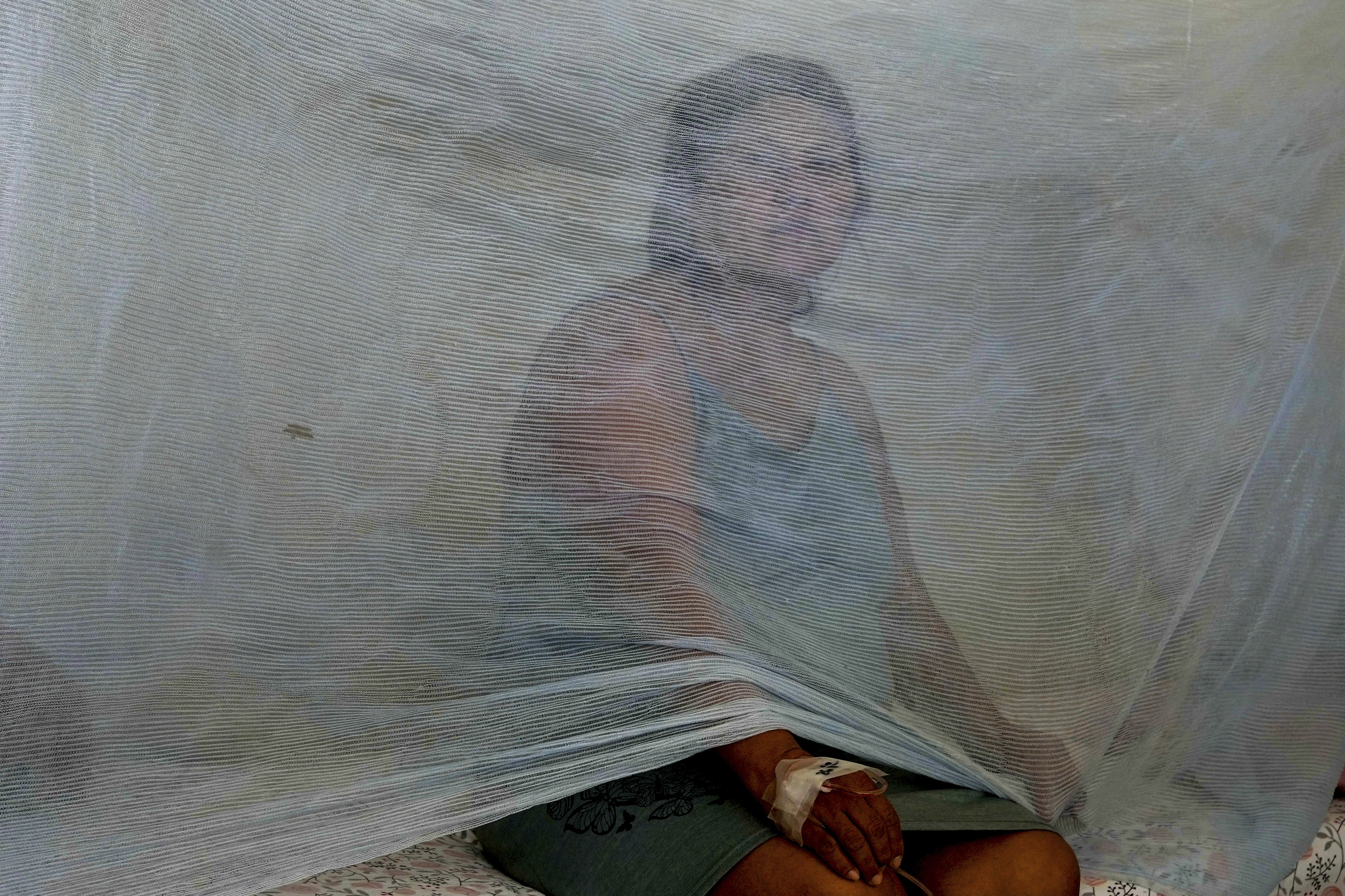 FILE - Jenny Chiroque sits on a bed with netting at La Merced Hospital where she is treated for dengue in Paita, Peru, Feb. 29, 2024. (AP Photo/Martin Mejia, File)