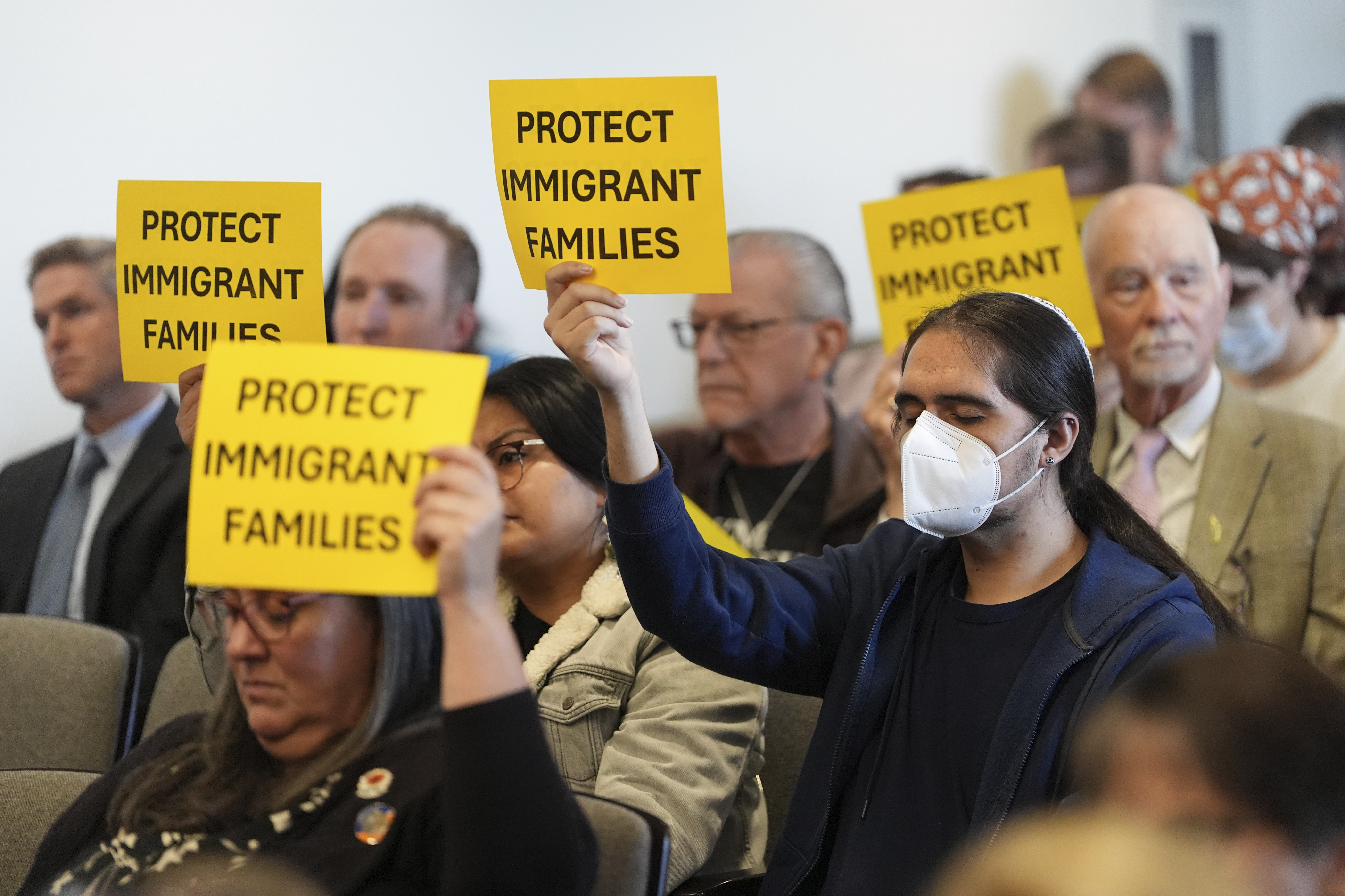 People hold signs during a San Diego County board of supervisors meeting Tuesday, Dec. 10, 2024, in San Diego. (AP Photo/Gregory Bull)