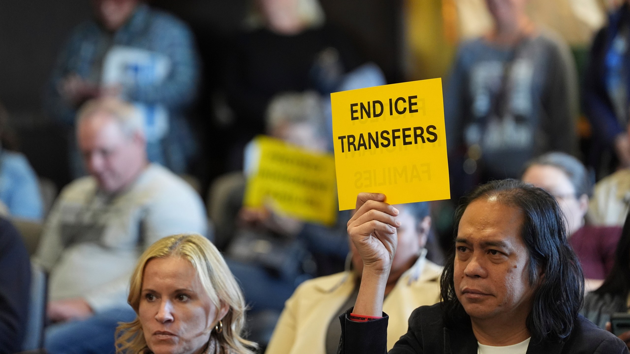 People hold signs during a San Diego County board of supervisors meeting Tuesday, Dec. 10, 2024, in San Diego. (AP Photo/Gregory Bull)