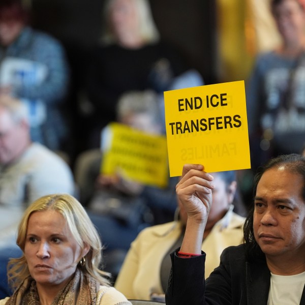 People hold signs during a San Diego County board of supervisors meeting Tuesday, Dec. 10, 2024, in San Diego. (AP Photo/Gregory Bull)