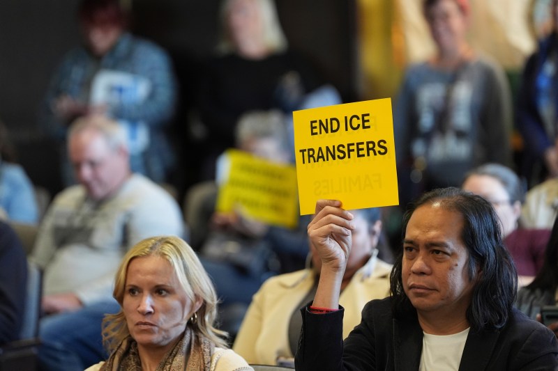 People hold signs during a San Diego County board of supervisors meeting Tuesday, Dec. 10, 2024, in San Diego. (AP Photo/Gregory Bull)