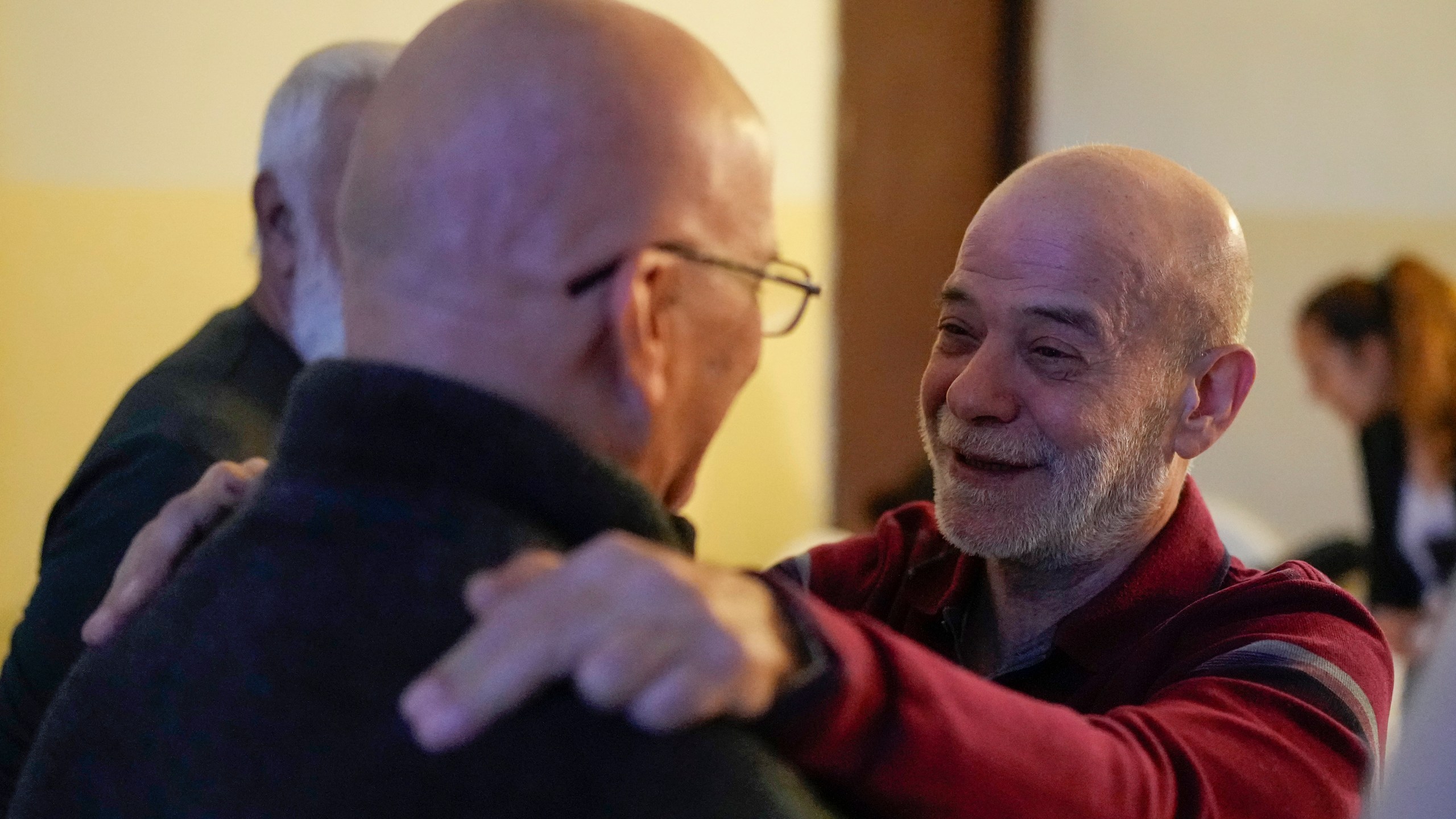 A neighbor welcomes Suheil Hamwi, right, who spent 32 years in prison in Syria, at Hamwi's home in Chekka, Lebanon, Tuesday, Dec. 10, 2024. (AP Photo/Hassan Ammar)