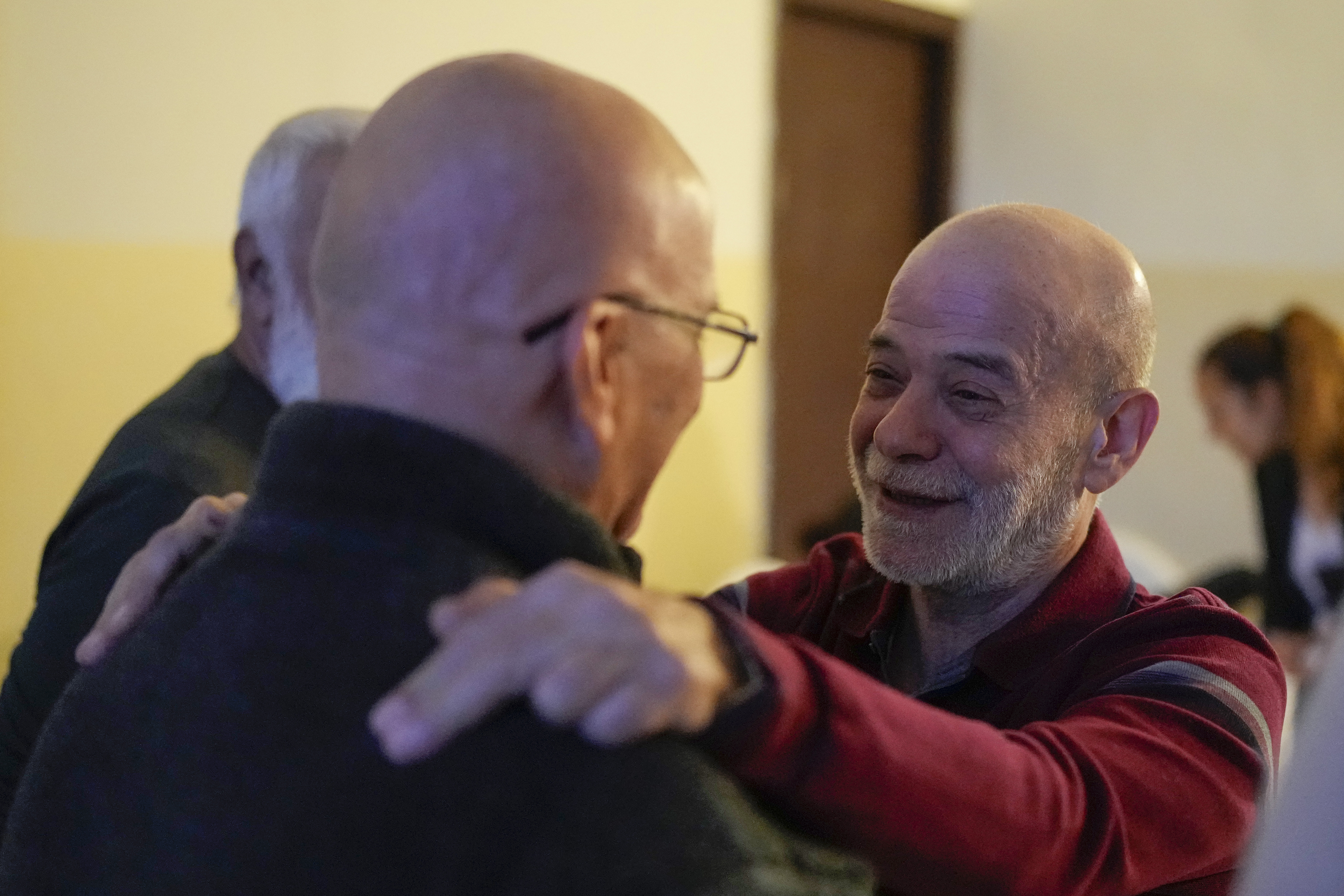 A neighbor welcomes Suheil Hamwi, right, who spent 32 years in prison in Syria, at Hamwi's home in Chekka, Lebanon, Tuesday, Dec. 10, 2024. (AP Photo/Hassan Ammar)