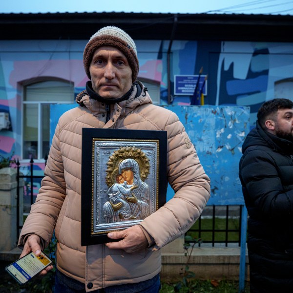 A man holds a religious icon outside the closed voting station where Calin Georgescu, an independent candidate for president who won the first round of presidential elections, was supposed to vote, after Romania's Constitutional Court annulled the first round of presidential elections, in Mogosoaia, Romania, Sunday, Dec. 8, 2024. (AP Photo/Andreea Alexandru)