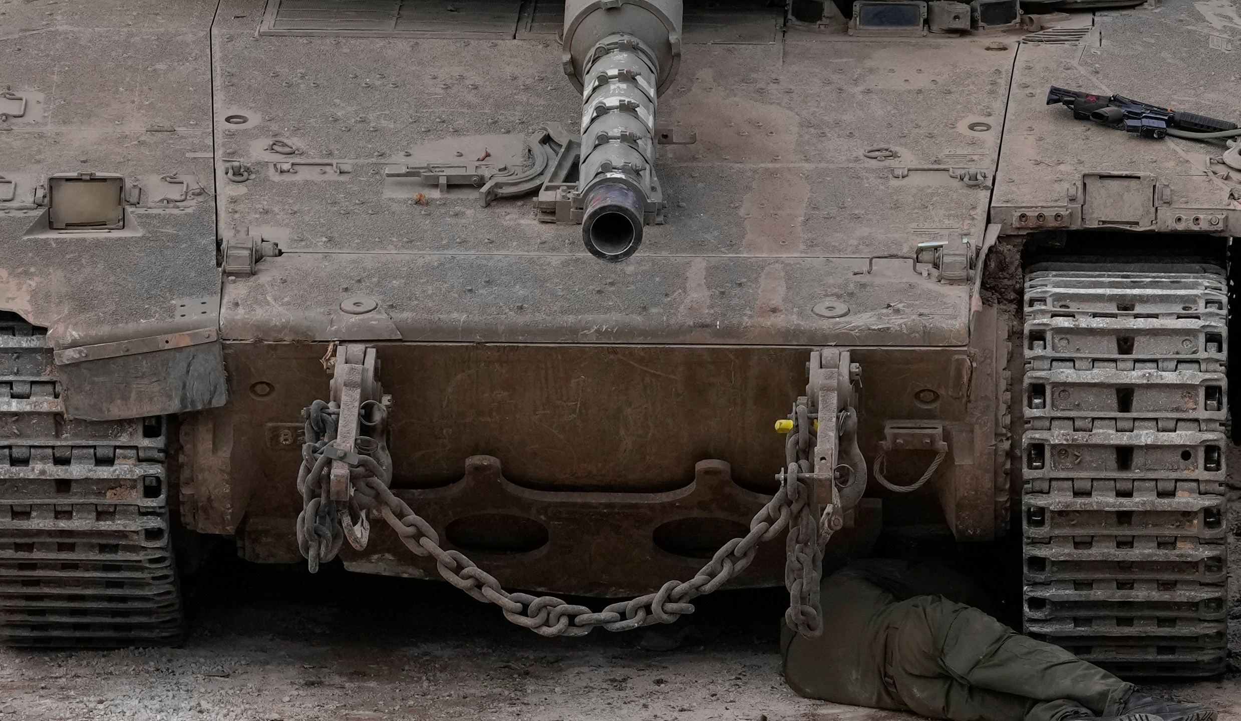 An Israeli soldier fixes a tank next to the security fence near the so-called Alpha Line that separates the Israeli-controlled Golan Heights from Syria, in the town of Majdal Shams, Wednesday, Dec. 11, 2024. (AP Photo/Matias Delacroix)