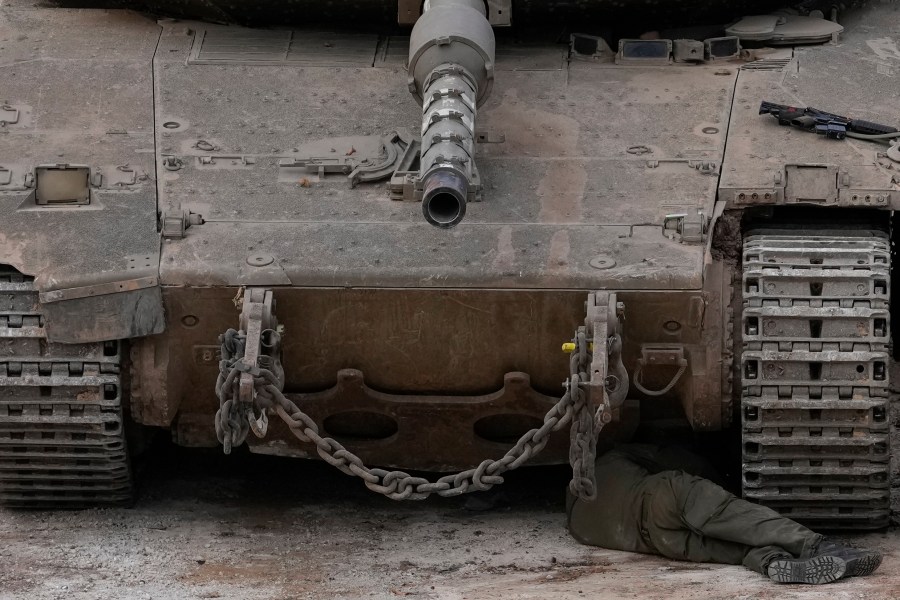 An Israeli soldier fixes a tank next to the security fence near the so-called Alpha Line that separates the Israeli-controlled Golan Heights from Syria, in the town of Majdal Shams, Wednesday, Dec. 11, 2024. (AP Photo/Matias Delacroix)