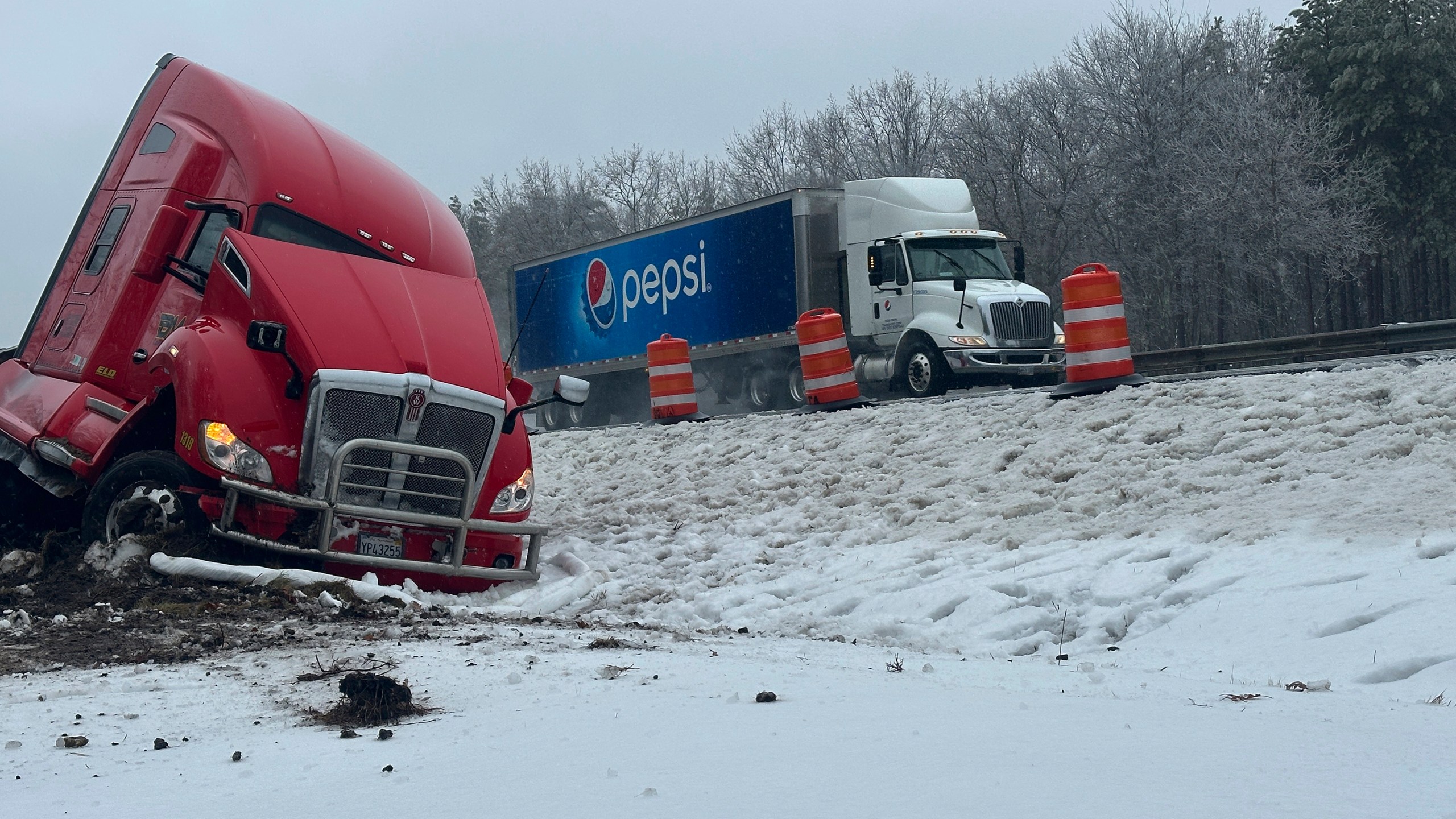 A tractor-trailer hauling a load of oranges sits on the side of the road after sliding off the Maine Turnpike early on Wednesday, Dec. 11, 2024, in New Gloucester, Maine. (AP Photo/David Sharp)