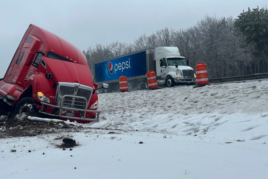 A tractor-trailer hauling a load of oranges sits on the side of the road after sliding off the Maine Turnpike early on Wednesday, Dec. 11, 2024, in New Gloucester, Maine. (AP Photo/David Sharp)