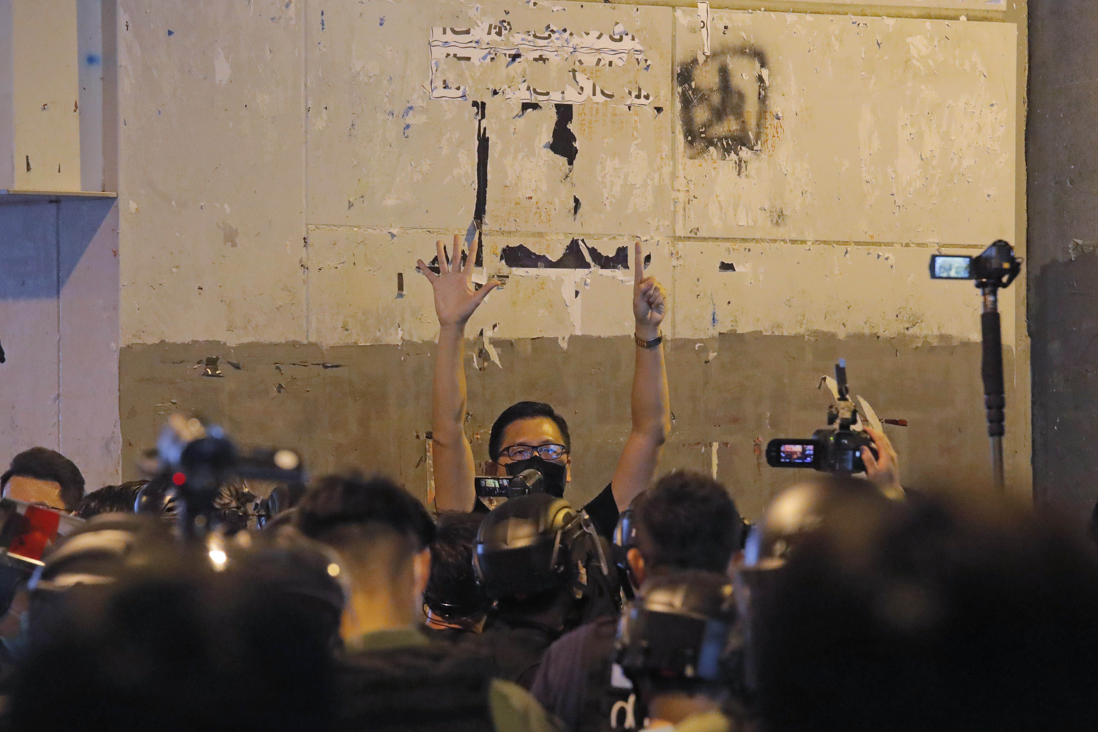 FILE- A pro-democracy lawmaker Lam Cheuk-ting, center, gestures with five fingers, signifying the "Five demands - not one less" as he is surrounded by riot police during a news conference to mark one-year anniversary of the Yuen Long subway attack at the subway station in Hong Kong, July 21, 2020. (AP Photo/Kin Cheung, File)