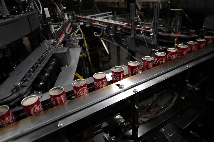 FILE - Coca-Cola cans move down a conveyer belt in the Swire Coca-Cola bottling plant Oct. 20, 2023, in Denver. (AP Photo/Brittany Peterson, File)