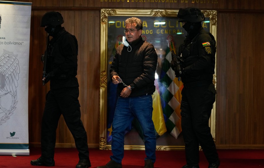 FILE - Police escort former anti-drug Director of the Bolivian police, Colonel Maximiliano Davila, as he is presented to the press at a Bolivian police command office after he was arrested on charges for being tied to a drug trafficking ring, in La Paz, Bolivia, Sunday, Jan. 23, 2022. (AP Photo/Juan Karita, File)