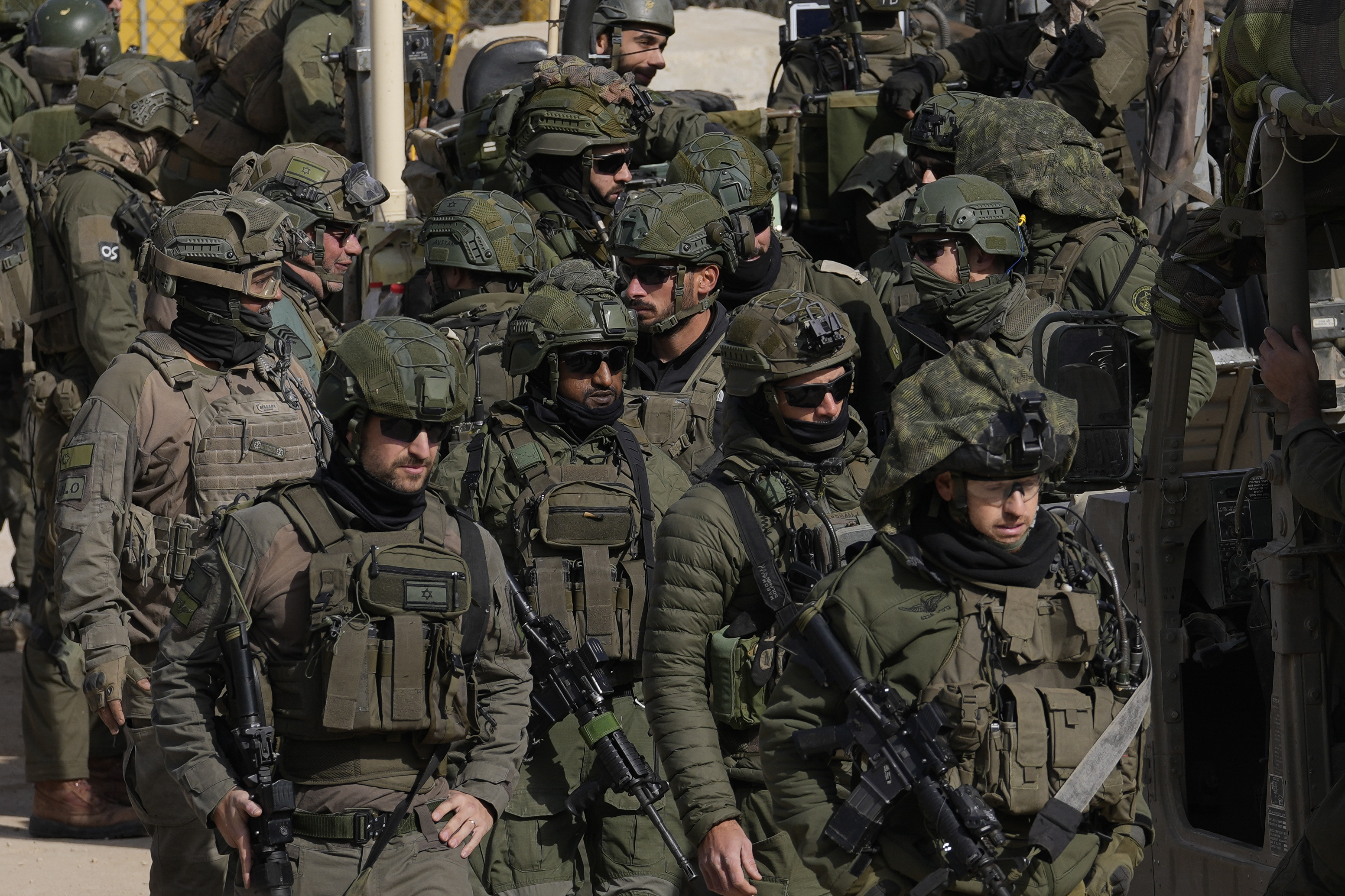 Israeli soldiers stand next to armoured vehicles before crossing the security fence, moving towards the so-called Alpha Line that separates the Israeli-controlled Golan Heights from Syria, in the town of Majdal Shams, Thursday, Dec. 12, 2024. (AP Photo/Matias Delacroix)