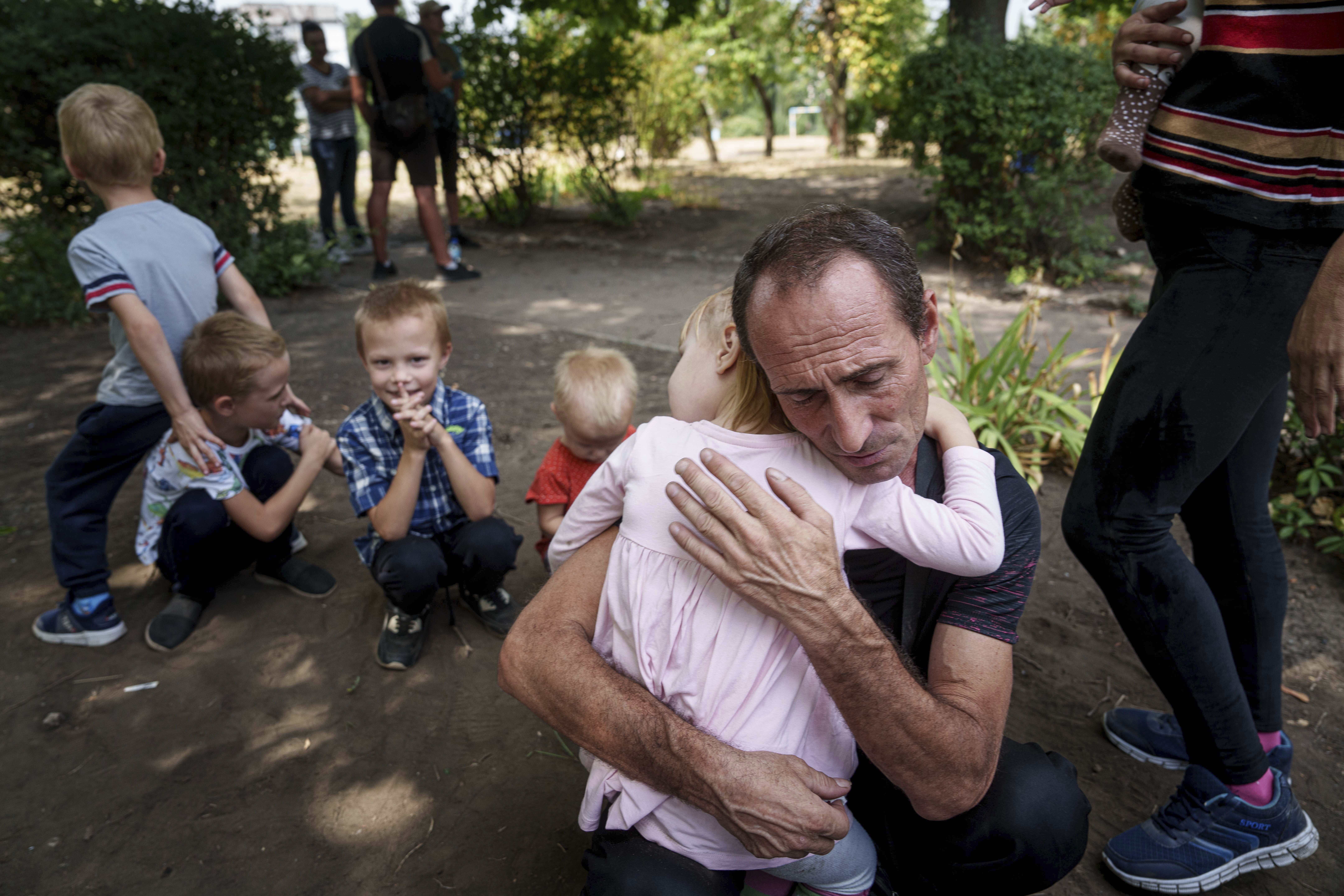 A father hugs his daughter, his other children nearby, as they wait for evacuation in Pokrovsk, Donetsk region, Ukraine, Friday, Aug. 23, 2024. (AP Photo/Evgeniy Maloletka)