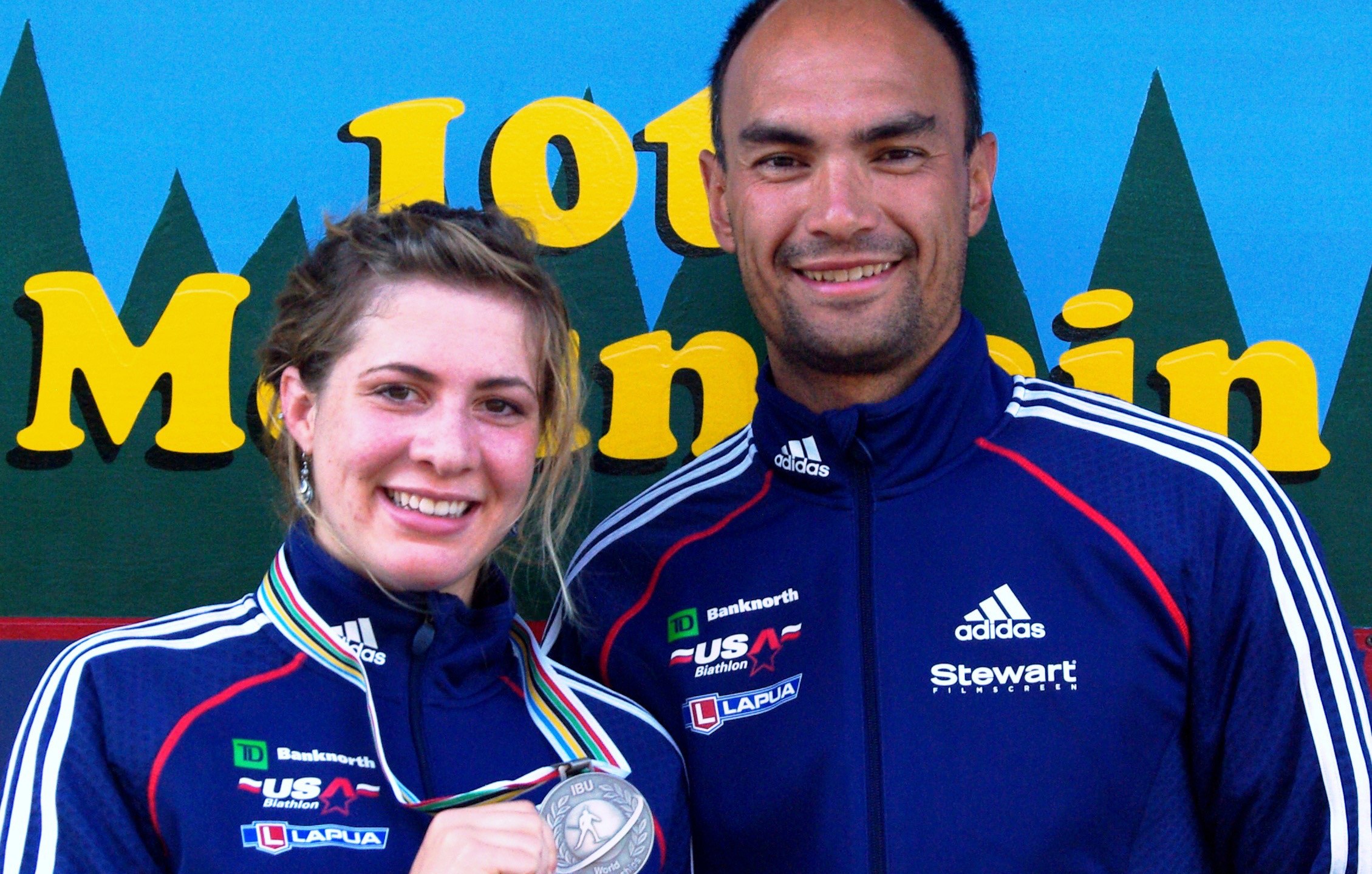 In this 2009 photo provided by Karen Gorman, biathlete Grace Boutot, left, of Fort Kent, Maine, displays her silver medal from the Youth Women Biathlon World Championships, while standing with coach Gary Colliander, right, in Fort Kent. (Karen Gorman via AP)