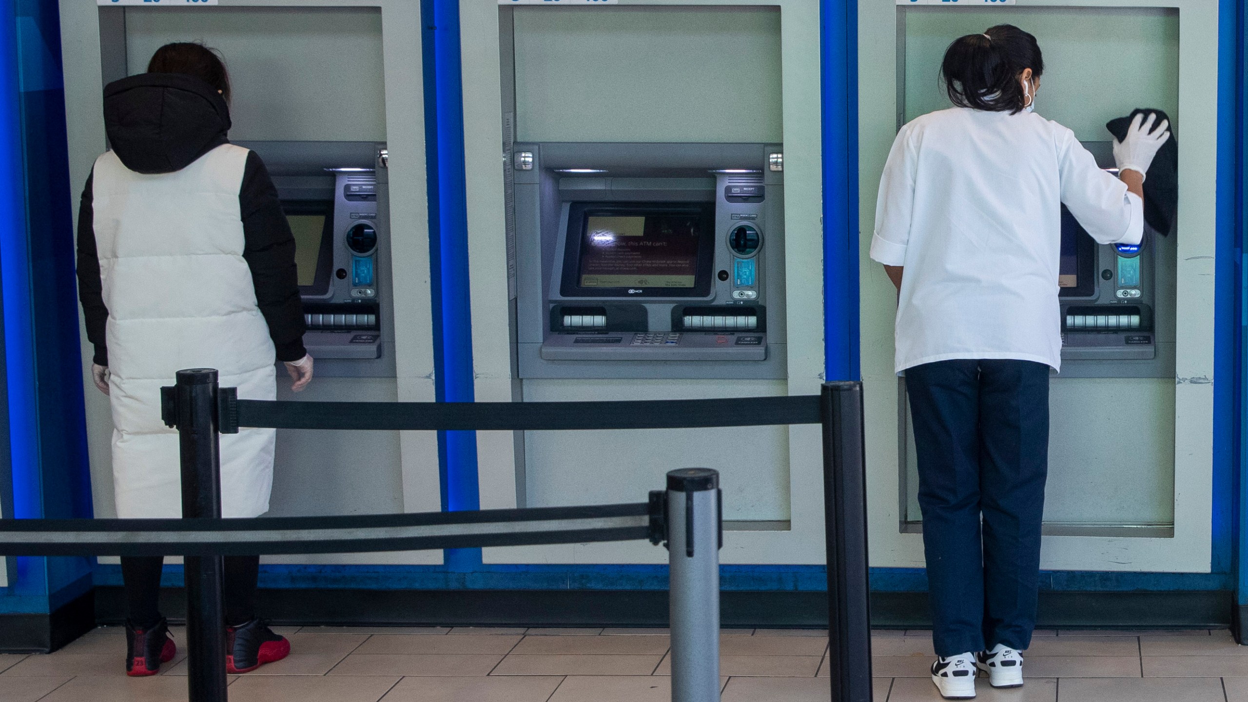 FILE - A customer makes a transaction at a bank of automatic teller machines in the Queens borough of New York on March 24, 2020. (AP Photo/Mary Altaffer, File)