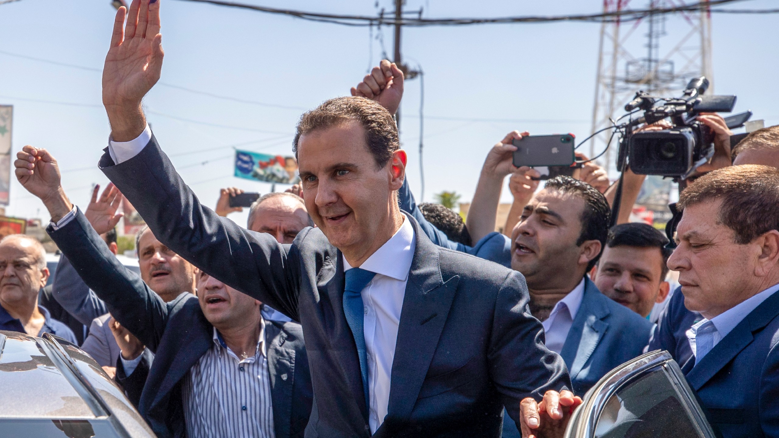 FILE - Then-President Bashar Assad, center, waves to his supporters at a polling station during presidential elections in the town of Douma, near the Syrian capital of Damascus, May 26, 2021. (AP Photo/Hassan Ammar, File)