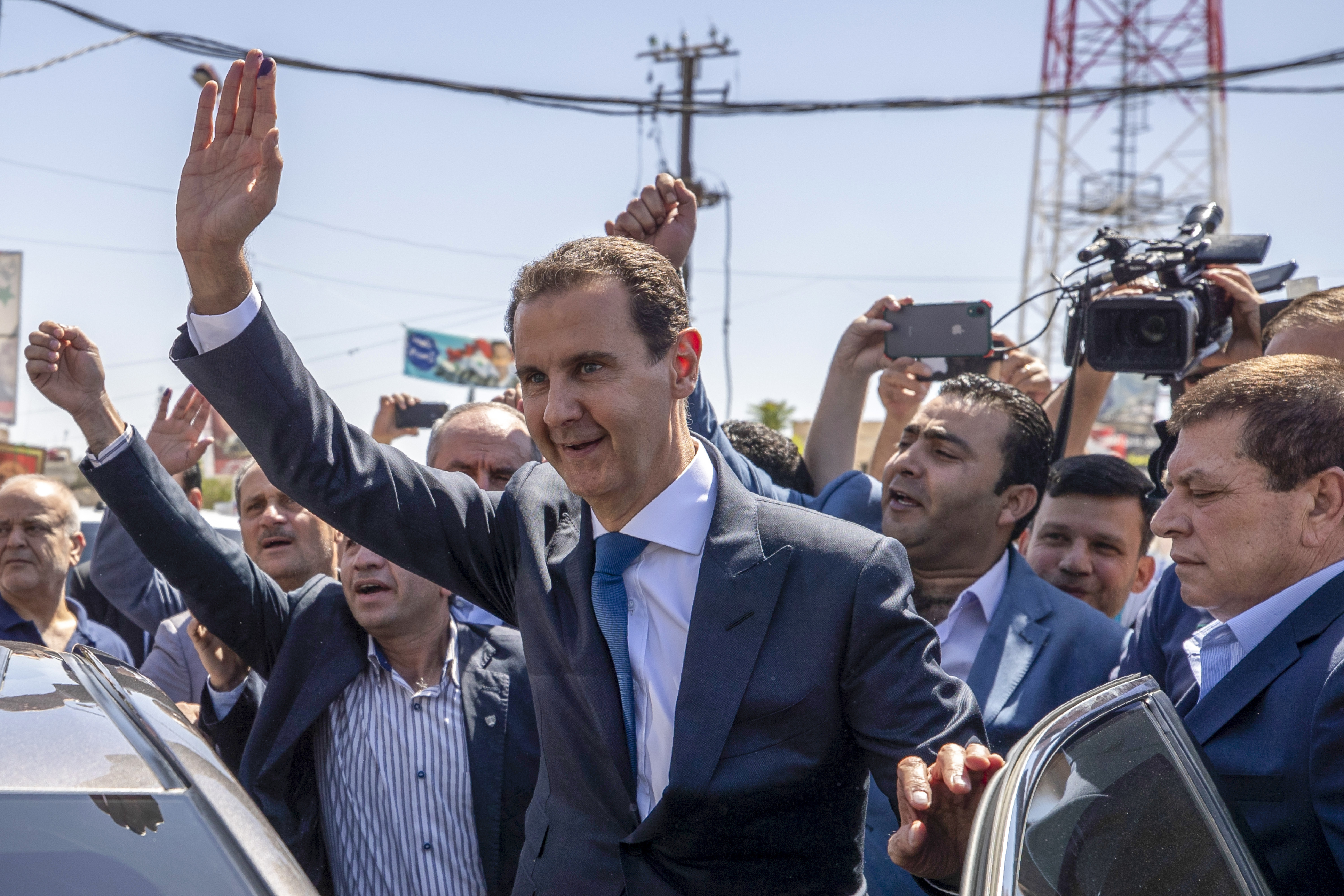 FILE - Then-President Bashar Assad, center, waves to his supporters at a polling station during presidential elections in the town of Douma, near the Syrian capital of Damascus, May 26, 2021. (AP Photo/Hassan Ammar, File)