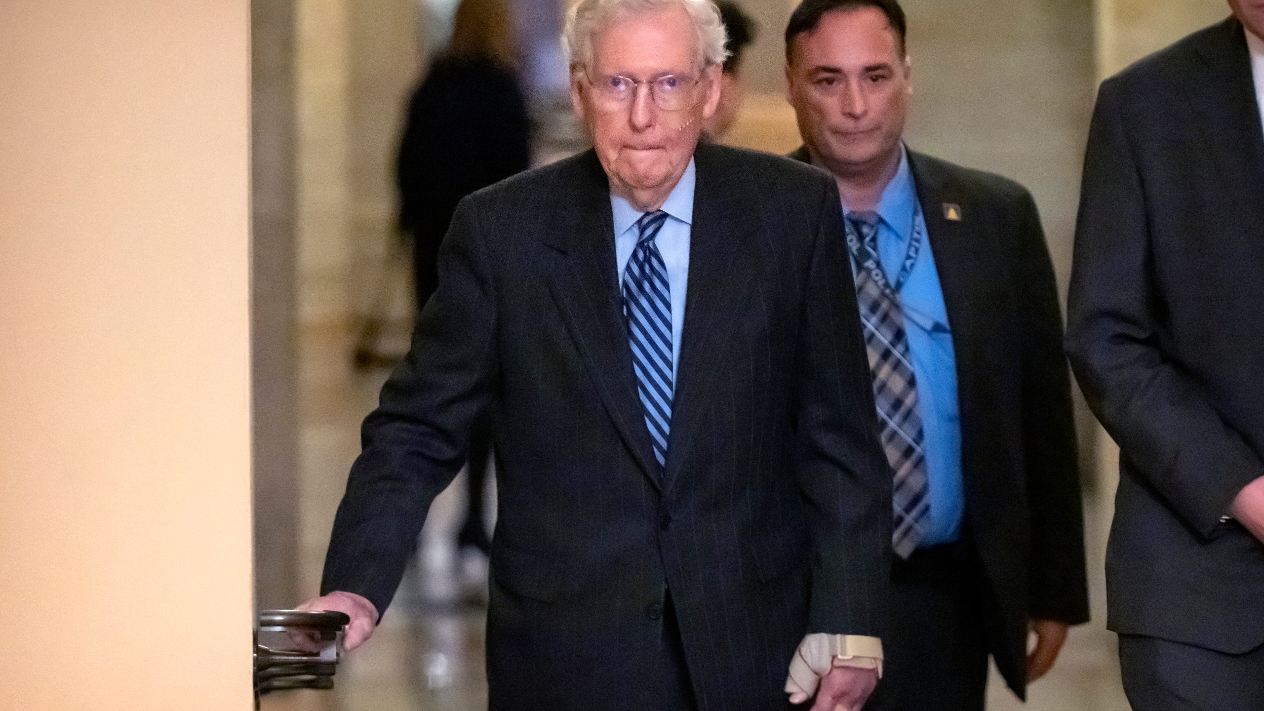 Senate Minority Leader Mitch McConnell of Ky., left, wears a bandage on his face and wrist as he walks to cast a vote on the Senate floor after falling during a luncheon on Capitol Hill, Tuesday, Dec. 10, 2024, in Washington. (AP Photo/Mark Schiefelbein)