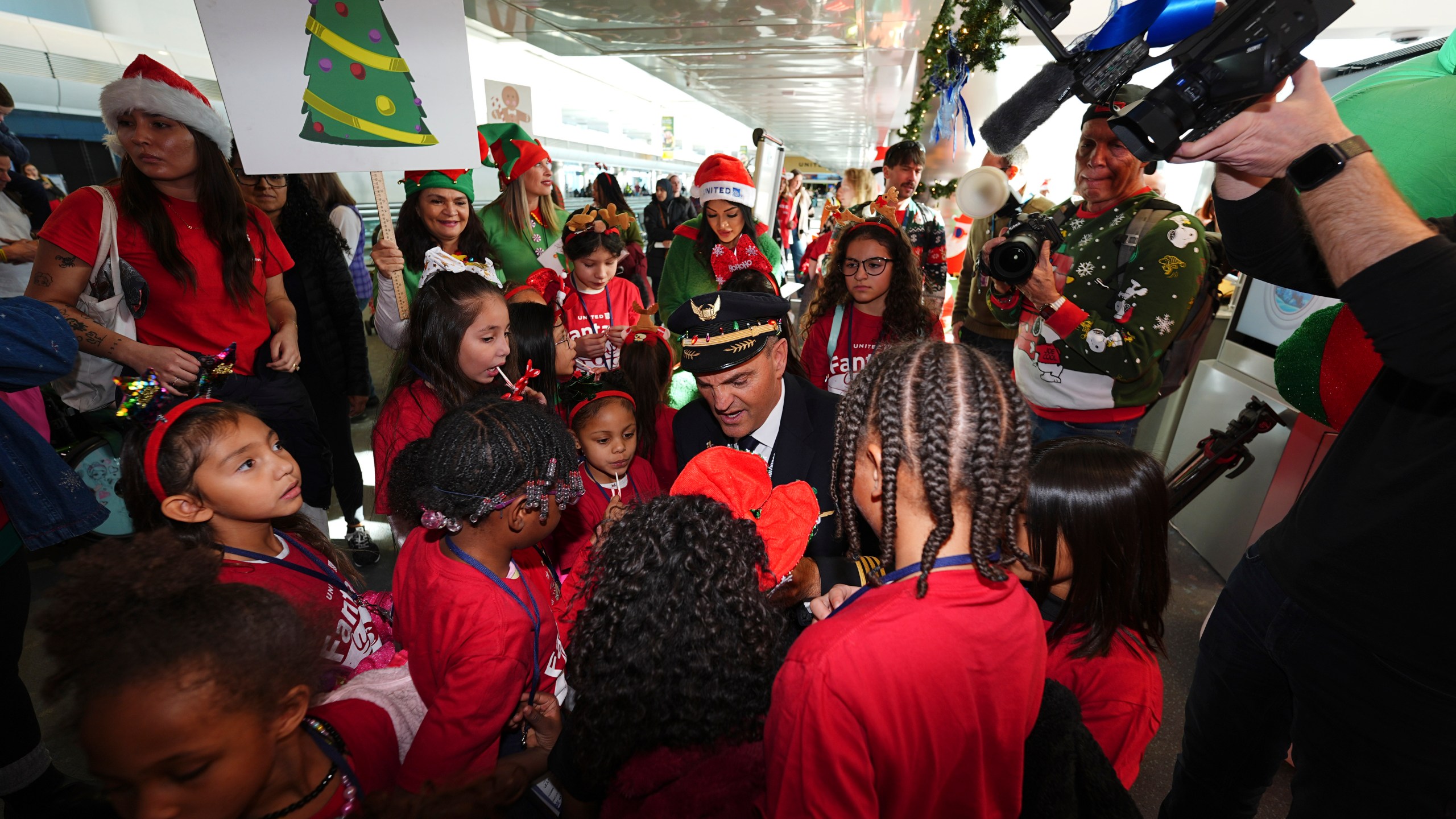 Captain Paul Purkey, center, pins wings on participants during the United Airlines annual "fantasy flight" to a fictional North Pole at Denver International Airport, Saturday, Dec. 14, 2024, in Denver. (AP Photo/David Zalubowski)