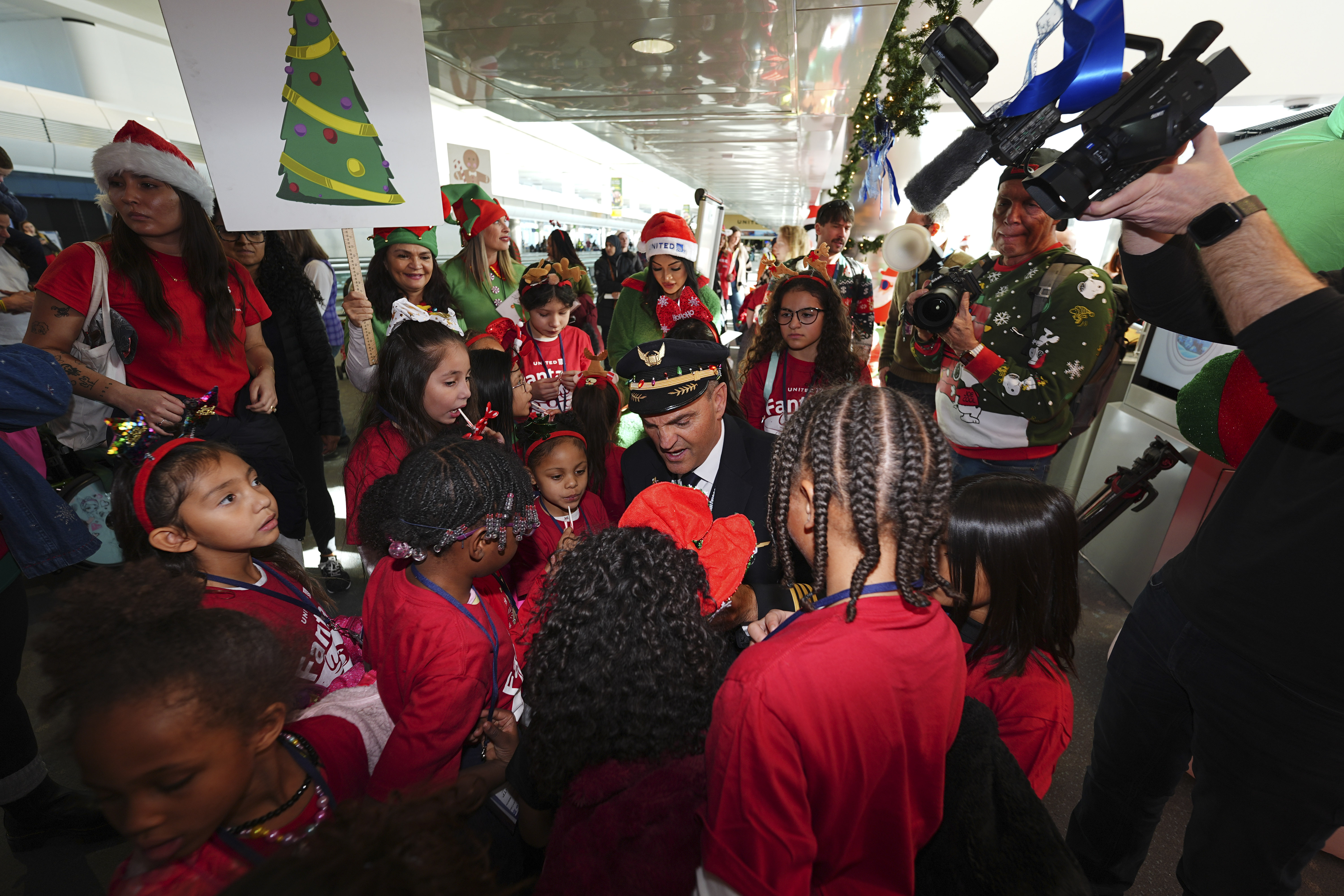 Captain Paul Purkey, center, pins wings on participants during the United Airlines annual "fantasy flight" to a fictional North Pole at Denver International Airport, Saturday, Dec. 14, 2024, in Denver. (AP Photo/David Zalubowski)