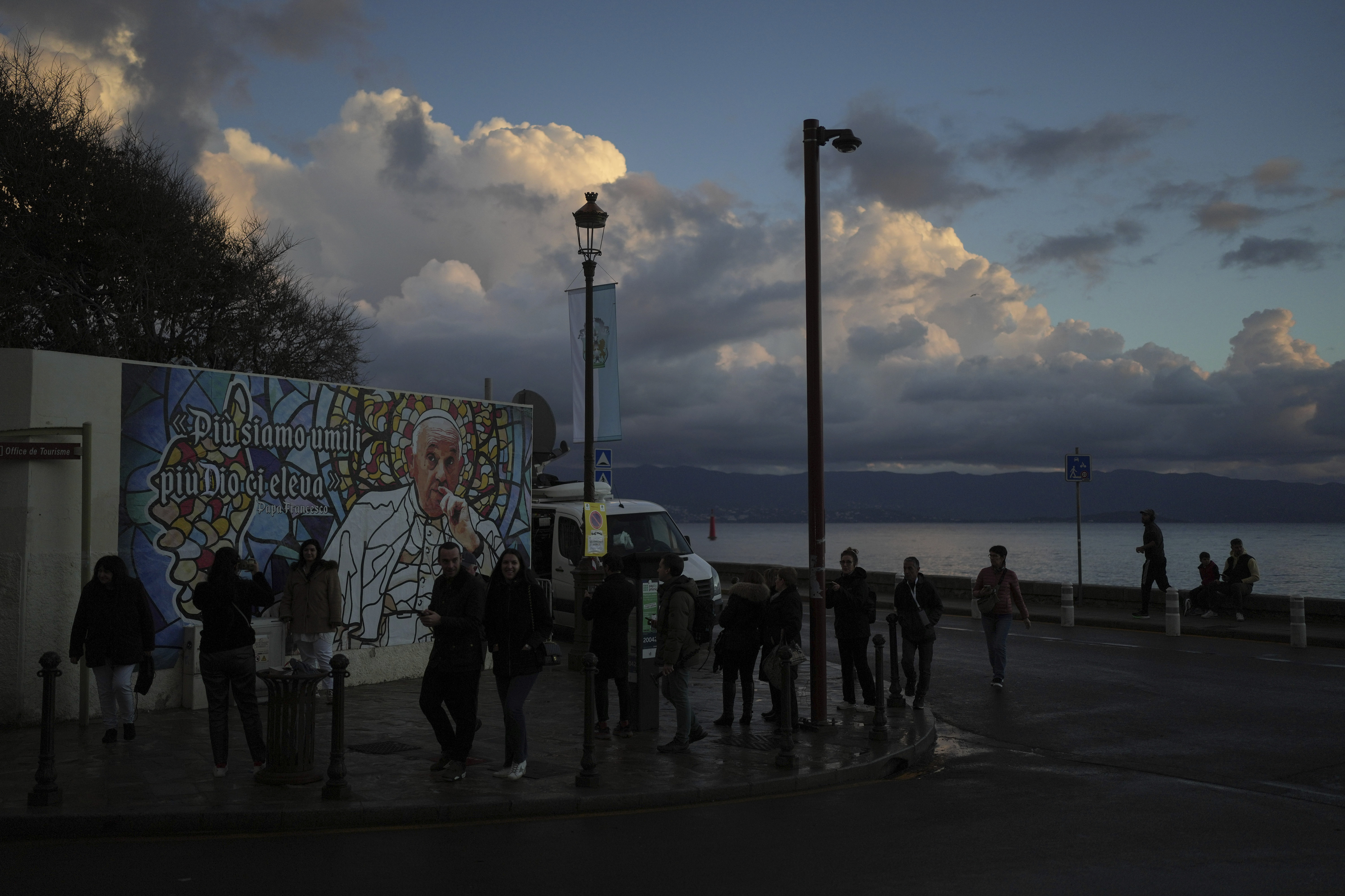 People walk past a mural featuring Pope Francis prior to the Pope's visit, in Ajaccio, in the southern French island of Corsica, Saturday, Dec. 14, 2024. (AP Photo/Thibault Camus)