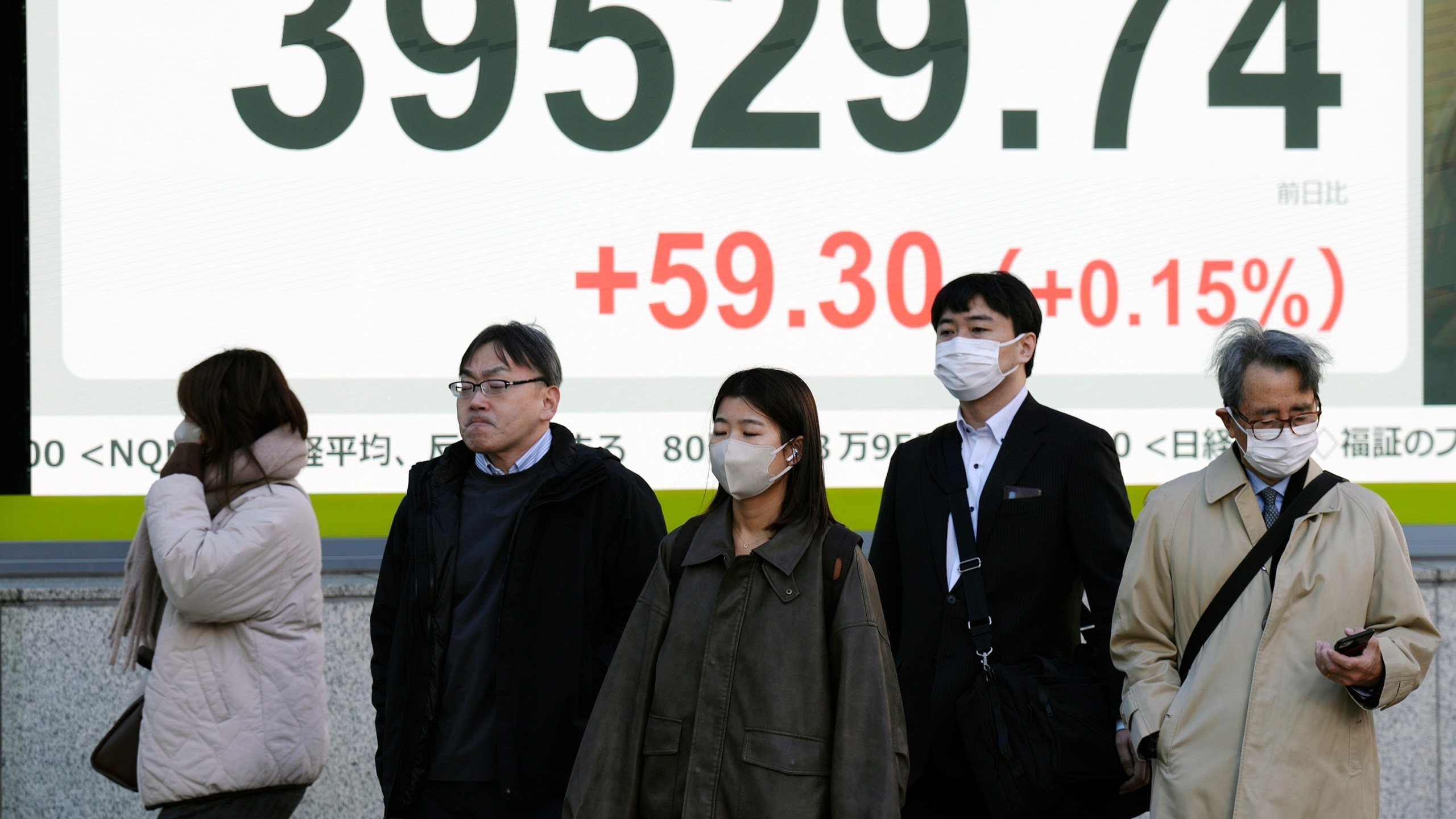 People stand in front of an electronic stock board showing Japan's Nikkei index at a securities firm Monday, Dec. 16, 2024, in Tokyo. (AP Photo/Eugene Hoshiko)