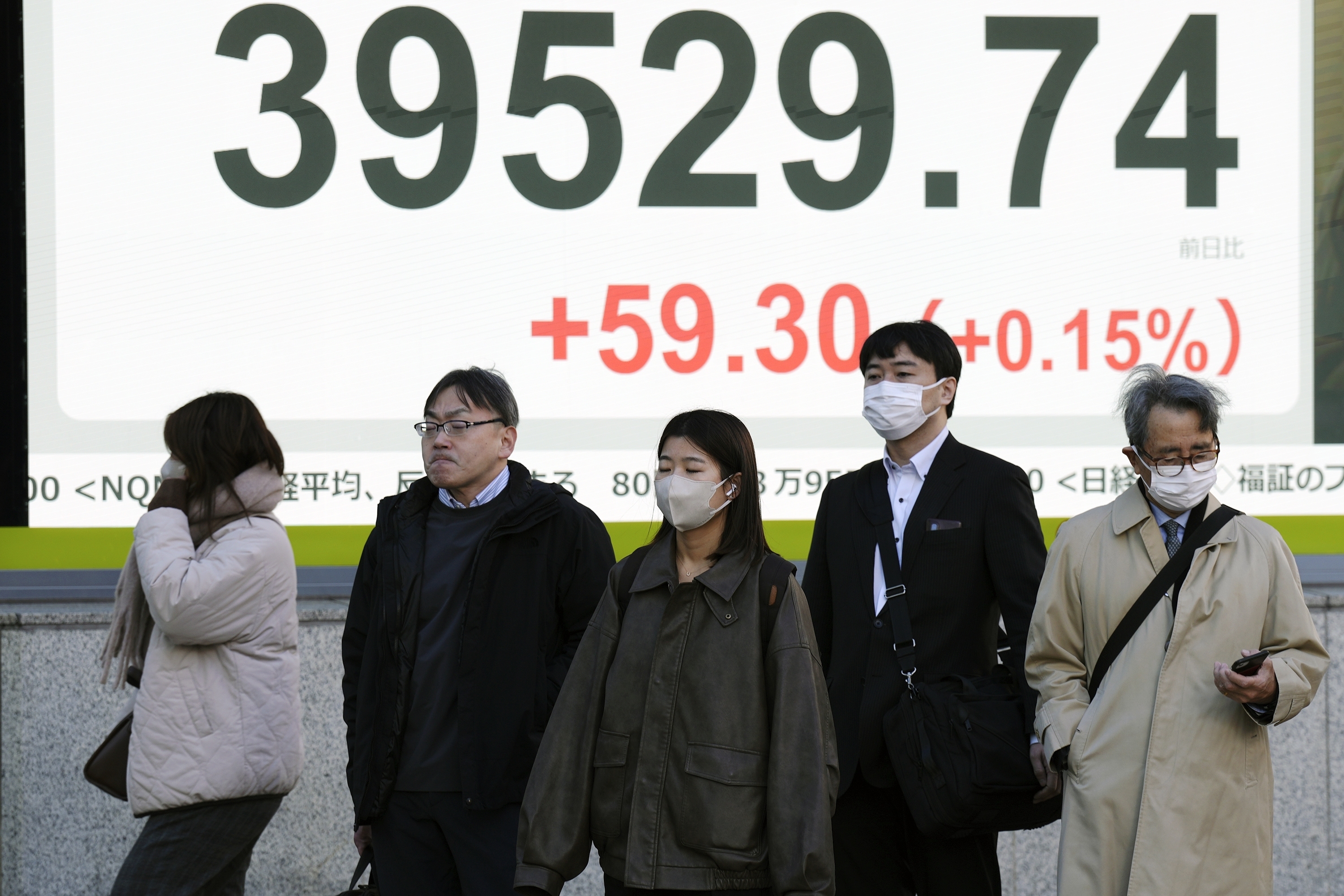 People stand in front of an electronic stock board showing Japan's Nikkei index at a securities firm Monday, Dec. 16, 2024, in Tokyo. (AP Photo/Eugene Hoshiko)